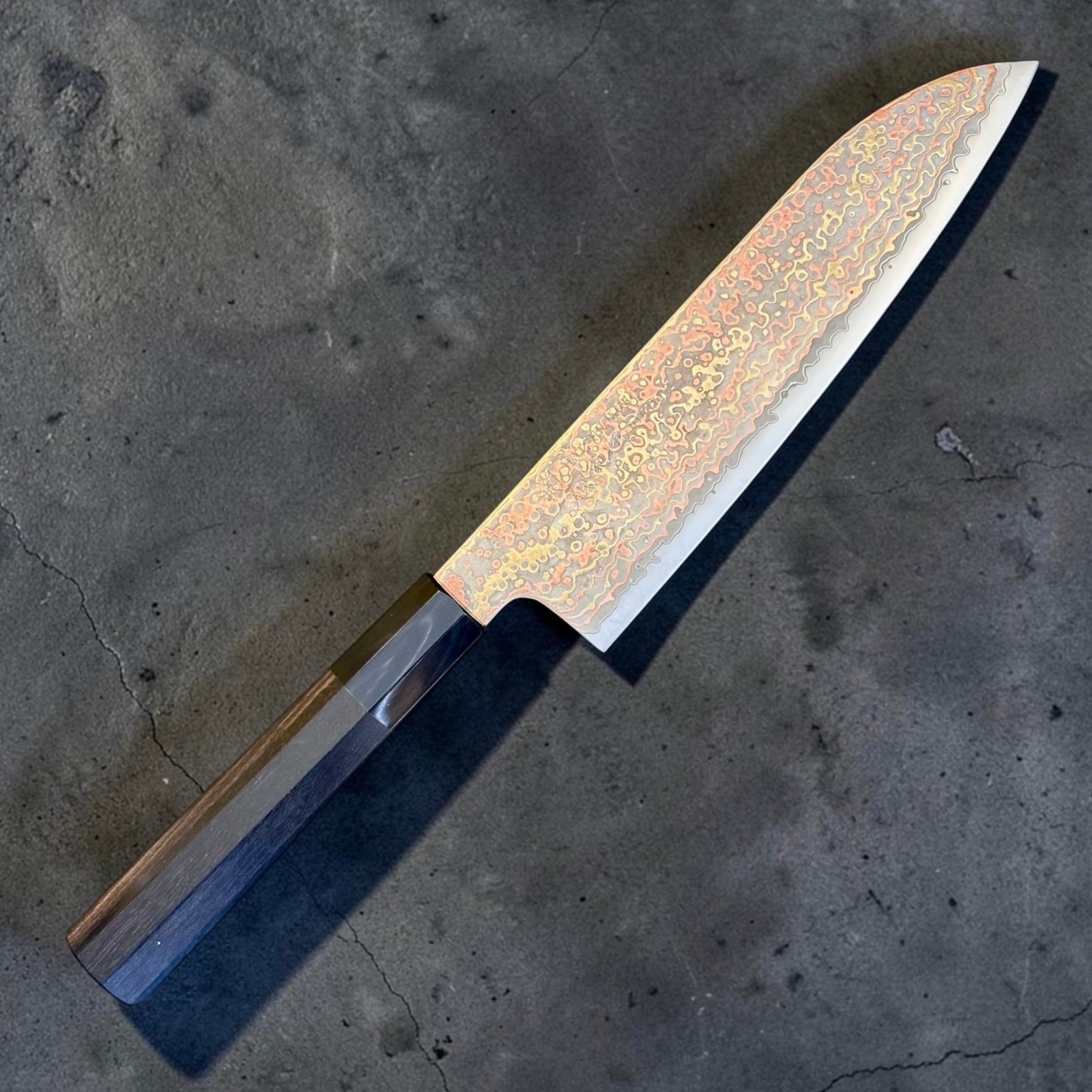 Angled view of Hatsukokoro Hinotori V-Toku 2 Santoku with ebony and black horn handle