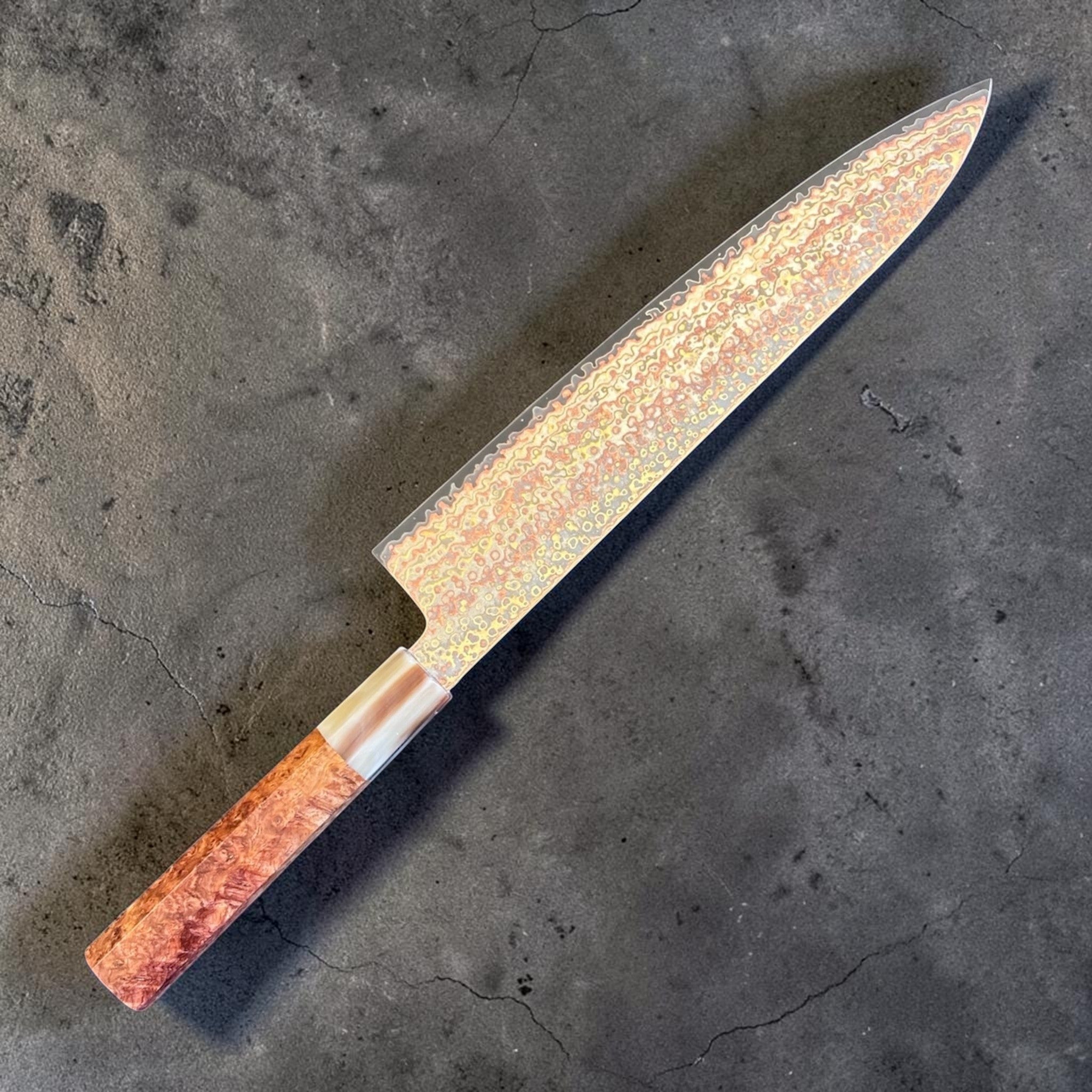 Hatsukokoro Hinotori V-Toku2 Rainbow Damascus Gyuto 240 mm with amboyna burl handle, angled studio view showing the rainbow Damascus pattern left side.