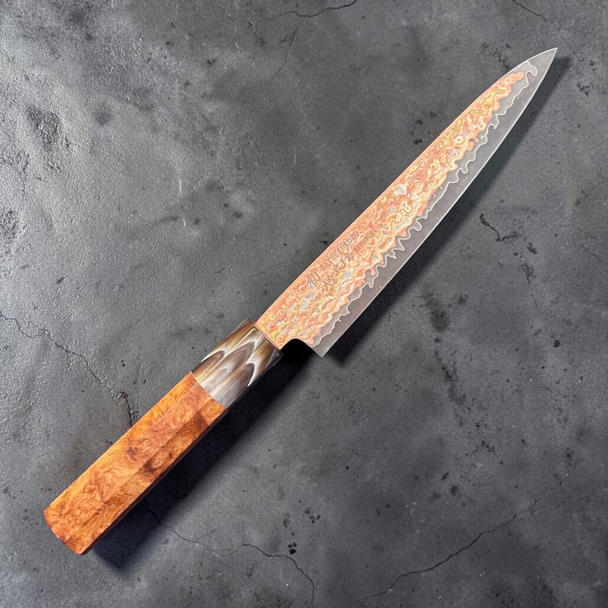 Hatsukokoro Hinotori V-Toku2 Rainbow Damascus Petty 150 mm with Amboyna Burl handle, angled full knife view showing iridescent rainbow Damascus blade.