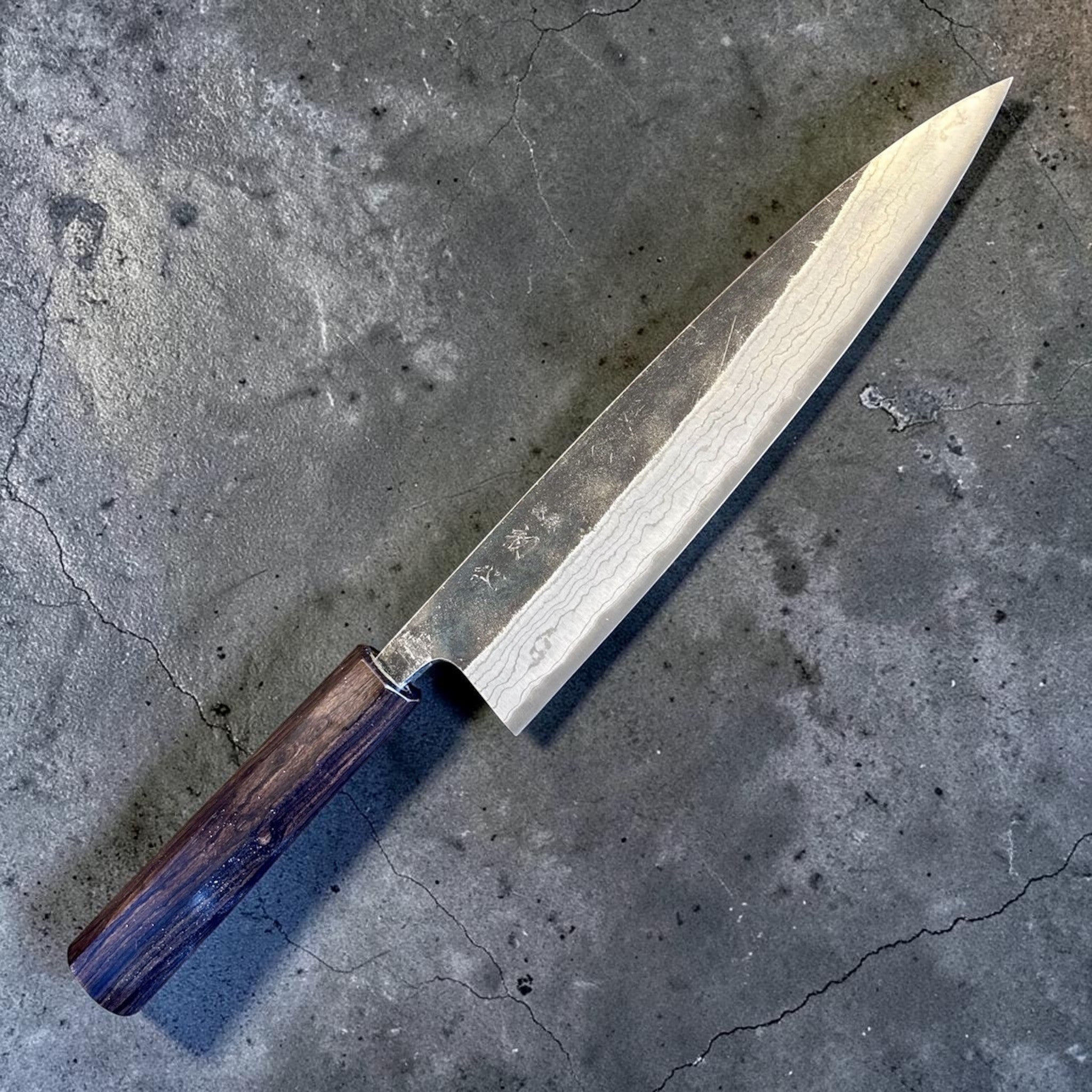 Hatsukokoro Kumokage Blue #2 Gyuto 240 mm with mono ebony handle, angled full-knife product view on a grey background.