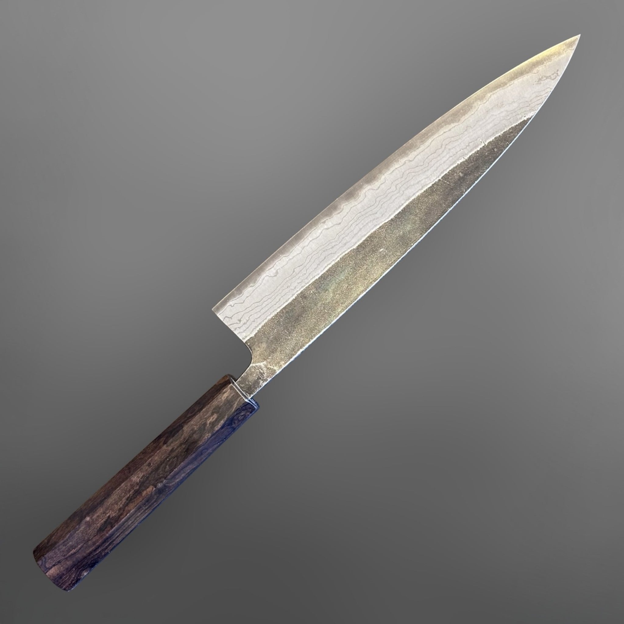 Hatsukokoro Kumokage Blue #2 Gyuto 240 mm with mono ebony handle, angled blade view highlighting the layered finish.