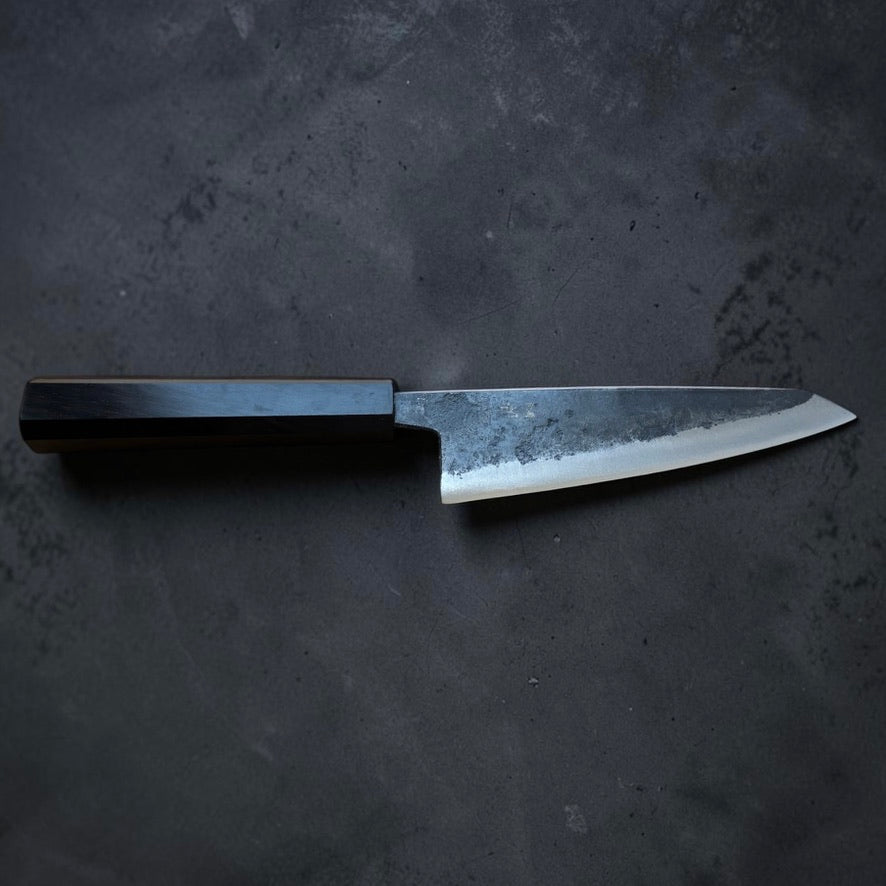Full side profile of the Hatsukokoro Kurogane Blue #2 Kurouchi Honesuki 150mm with mono ebony handle.