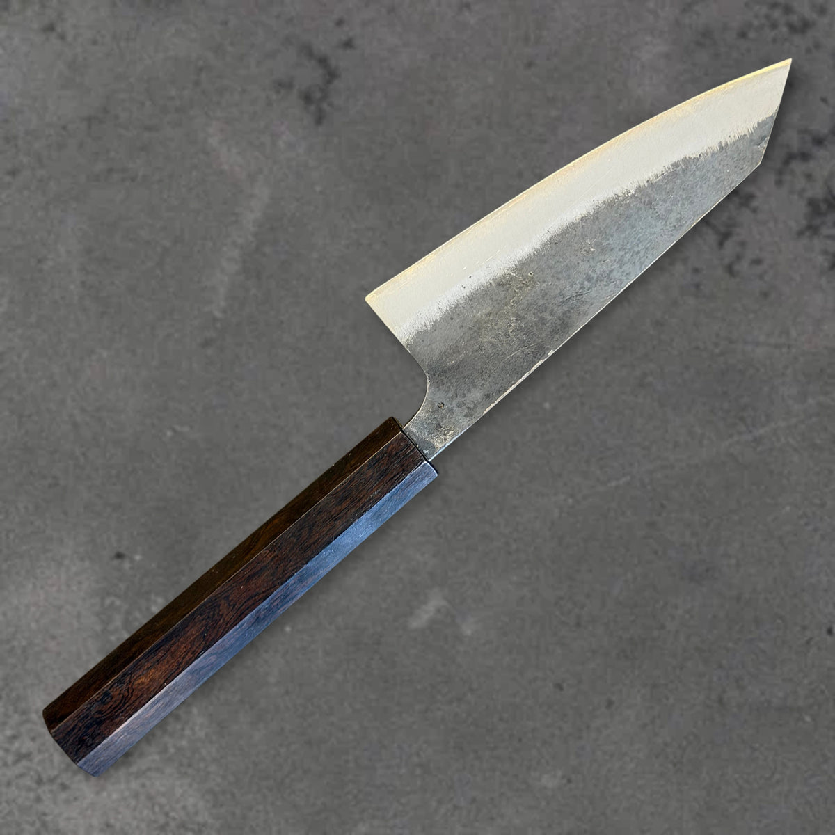 Angled reverse view of the Hatsukokoro Kurogane Blue #2 Kurouchi 120mm ko-bunka with ebony handle, showing the blade shape, finish, and handle.