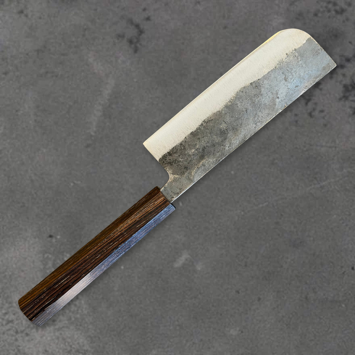 Angled reverse view of the Hatsukokoro Kurogane Blue #2 Kurouchi 120mm nakiri with ebony handle, showing the blade shape, finish, and handle. #Handle_Mono Ebony