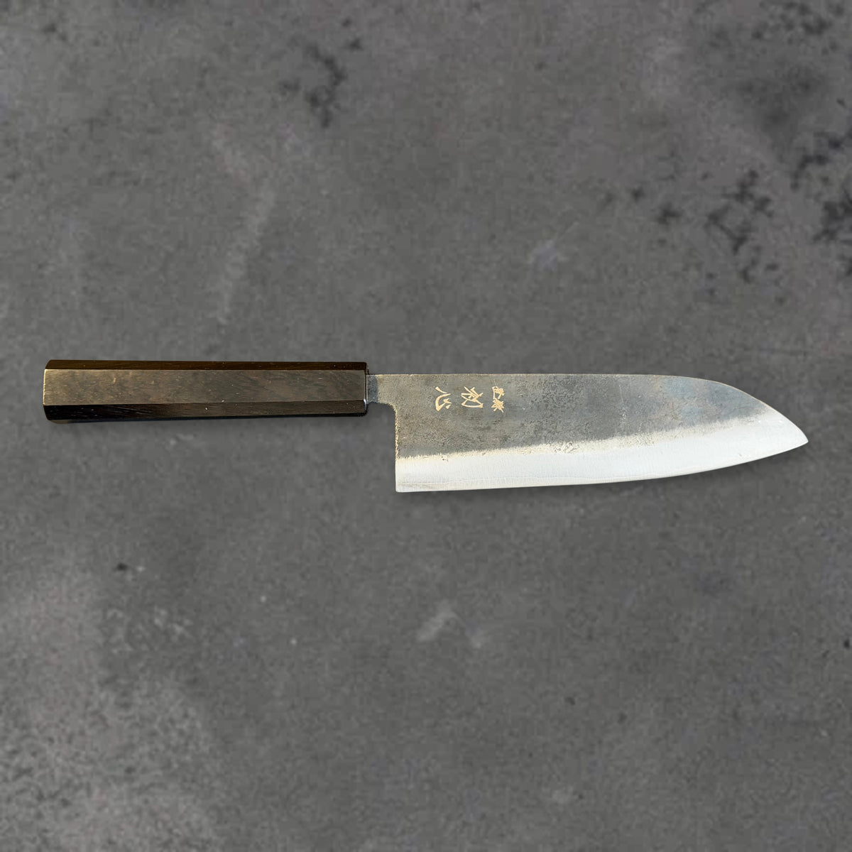 Hatsukokoro Kurogane Blue #2 Kurouchi 165mm santoku with ebony handle, shown in horizontal front profile with the full blade and handle visible.
