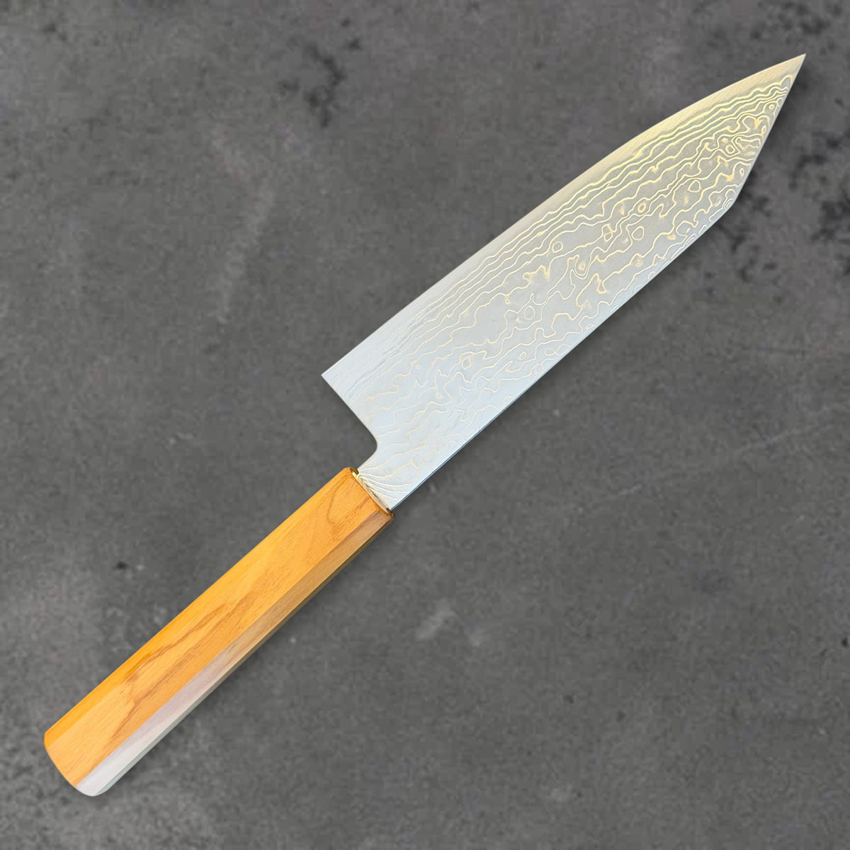 Angled reverse view of the Hatsukokoro Ryuhyo SG2 Damascus 180mm bunka with olive wood handle, showing the blade shape, finish, and handle. #Handle_Mono Olive Wood