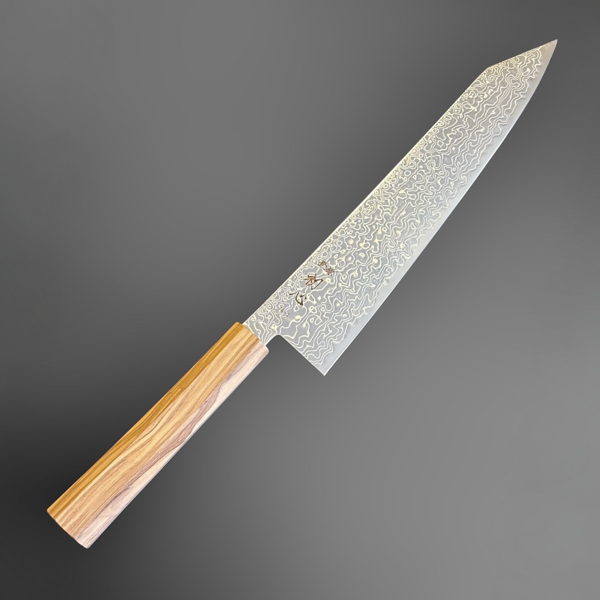 Hatsukokoro Ryuhyo SG2 Damascus Migaki Kiritsuke 240 mm with olive wood handle, angled full-length view showing the pointed kiritsuke tip and flowing Damascus pattern.