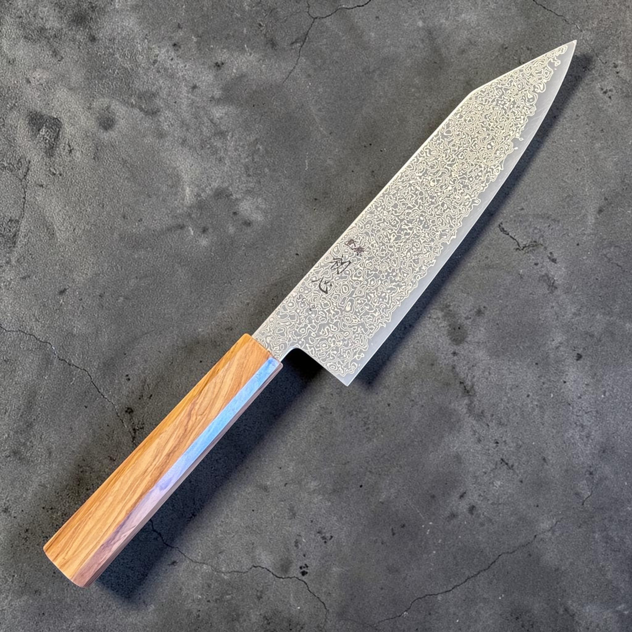 Hatsukokoro Saihyo SG2 Damascus Bunka 180 mm with olivewood handle, full side profile showing the entire blade and handle.