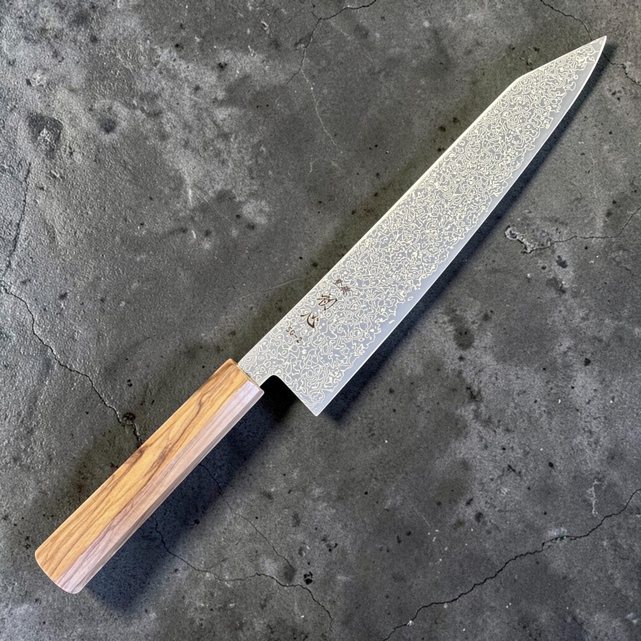 Hatsukokoro Saihyo SG2 Damascus Kiritsuke 240mm with Mono Olive Wood Handle, angled full-length product view showing the SG2 Damascus kiritsuke blade and mono olive wood wa handle.