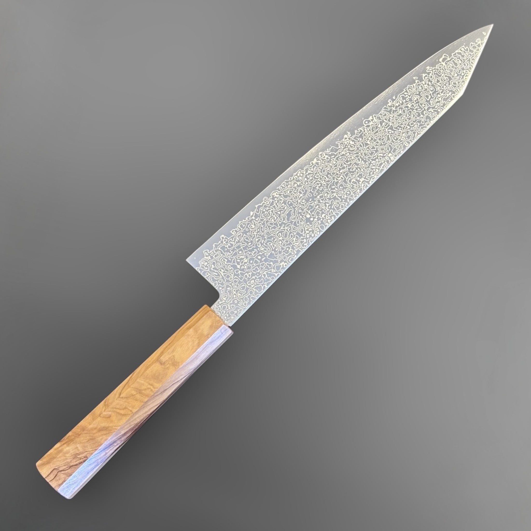 Hatsukokoro Saihyo SG2 Damascus Kiritsuke 240mm with Mono Olive Wood Handle, alternate angled full-length product view highlighting the Damascus pattern and pale olive wood handle.