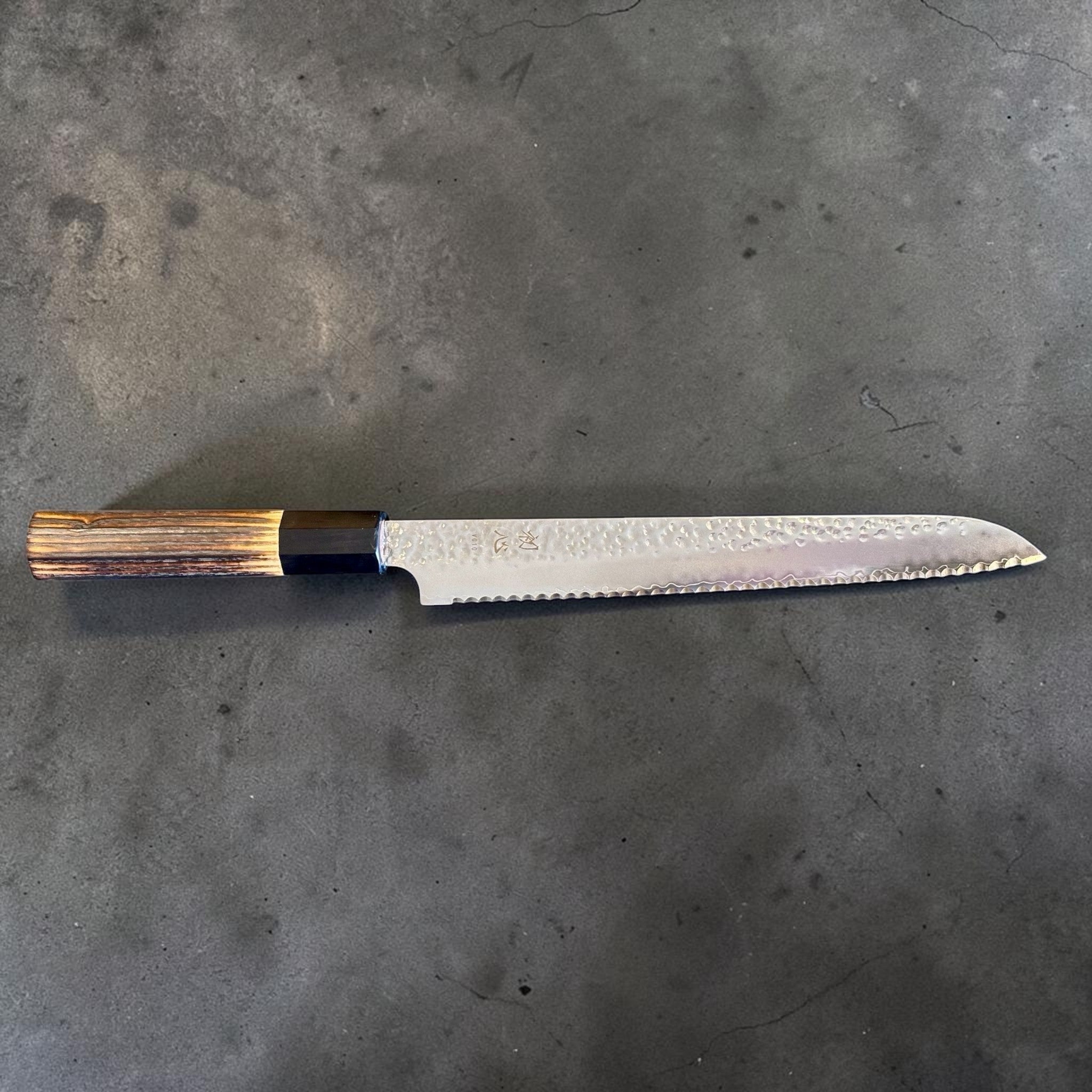 Hatsukokoro VG-10 Tsuchime Serrated Bread Knife 230 mm with burnt wood and black buffalo horn handle, full side profile showing serrated bread knife blade and burnt wood wa handle.