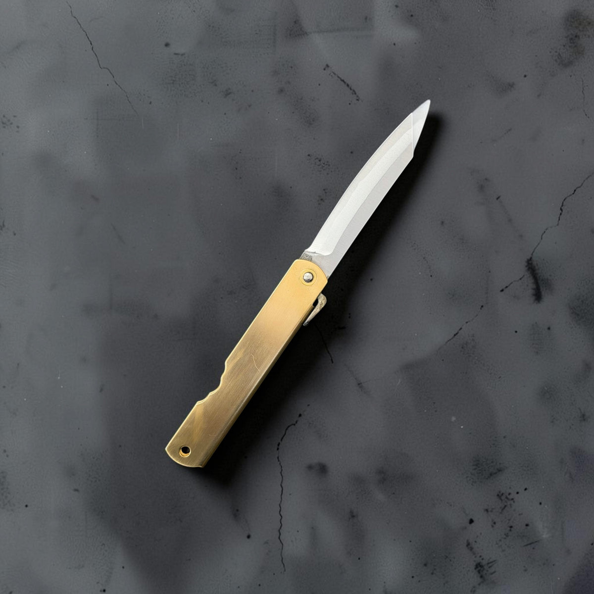 Reverse side of the open Higonokami Blue #2 medium pocket knife with its folded brass handle and polished blade.