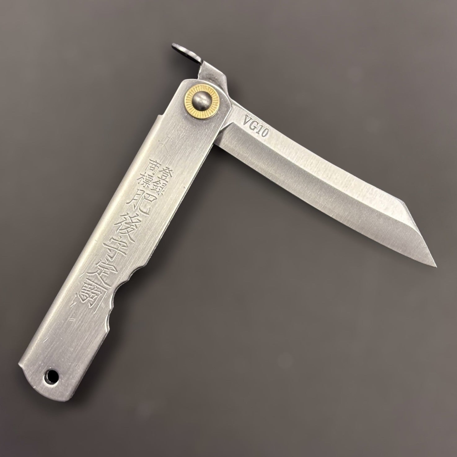 Higonokami VG-10 Japanese pocket knife, medium size, diagonal open view on dark background.