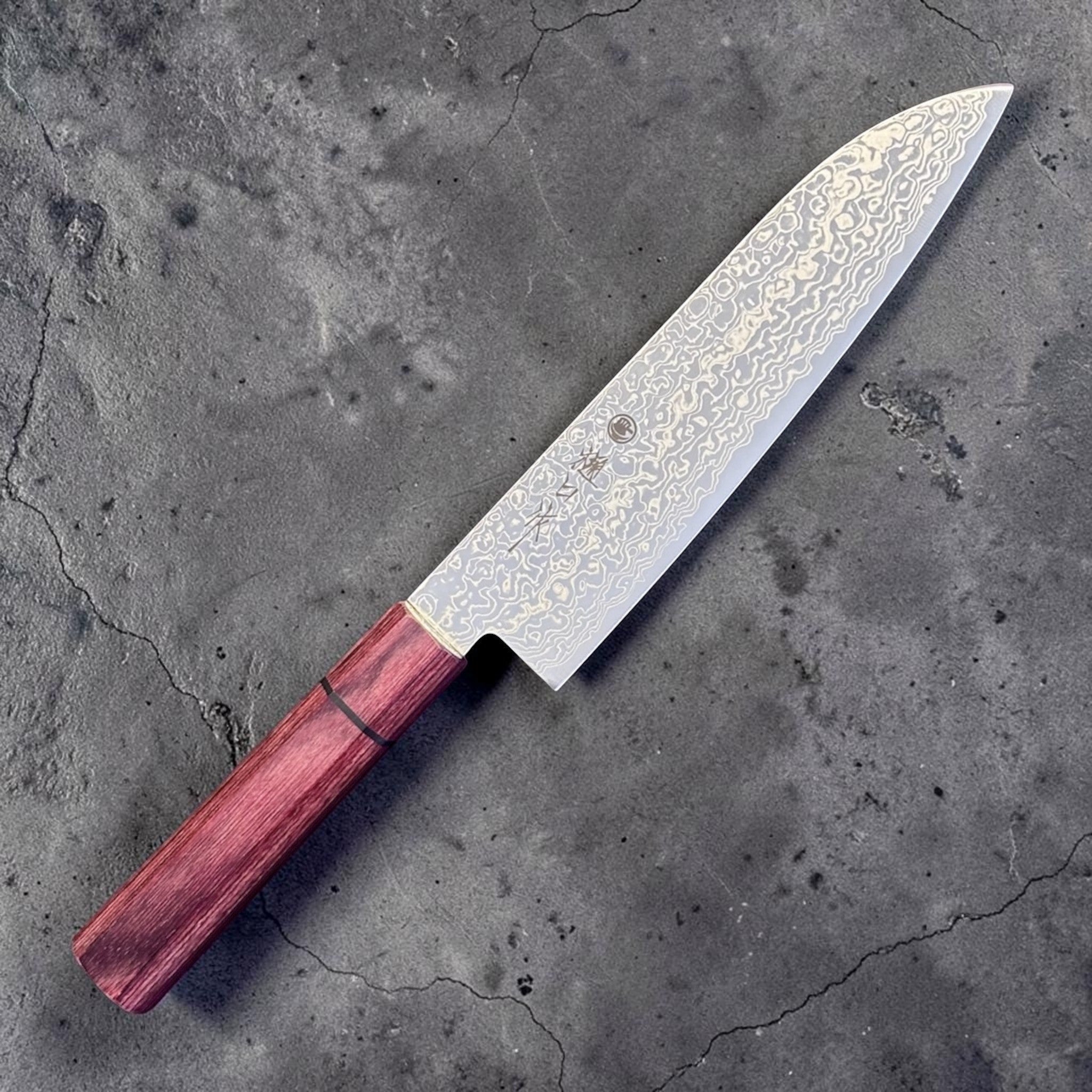 Higuchi SG2 Damascus Santoku 180 mm with red pakkawood handle, close-up angled view of the SG2 Damascus blade face.
