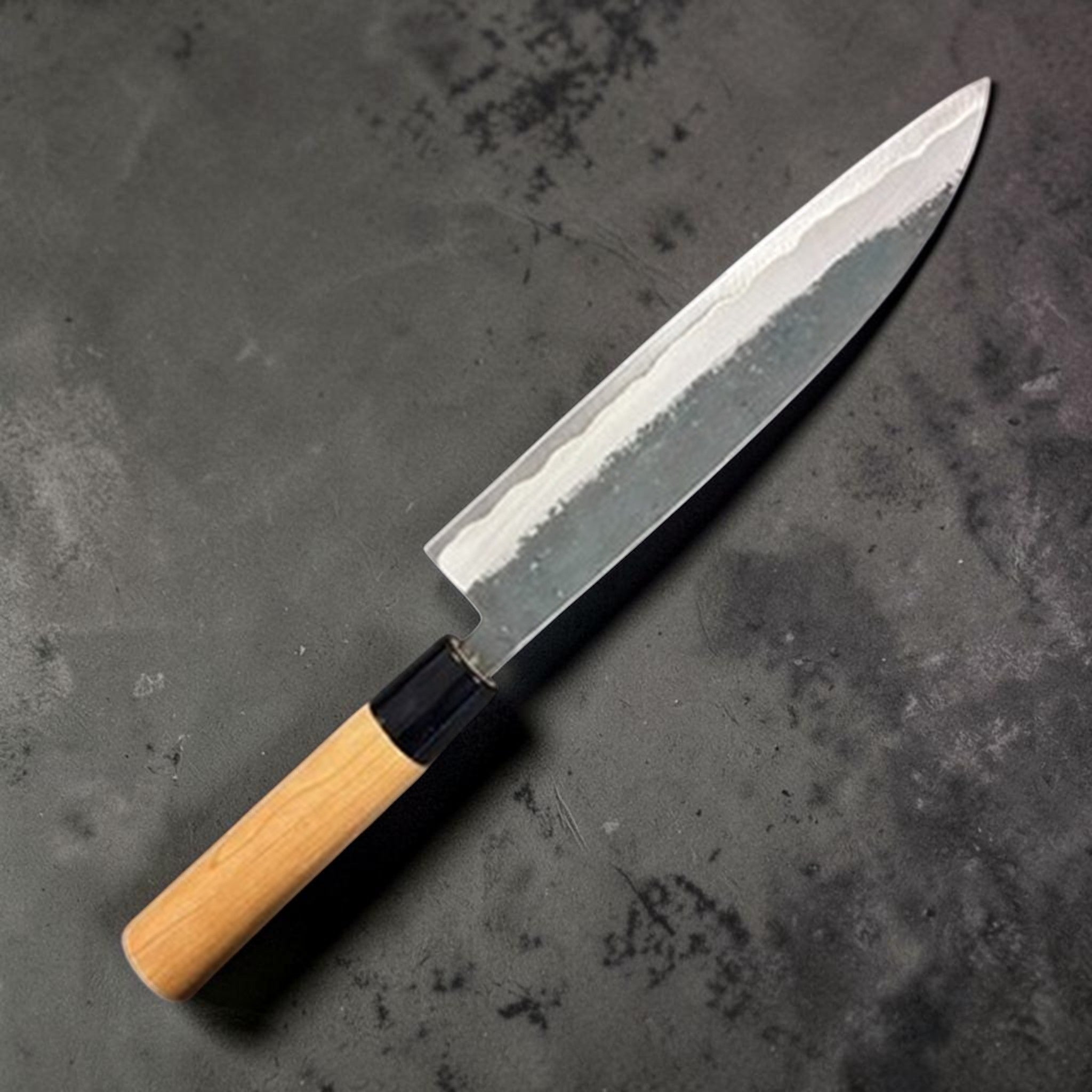 Hinokuni Aogami Super Kurouchi Gyuto 210 mm, opposite side three‑quarter view highlighting the core/cladding line.