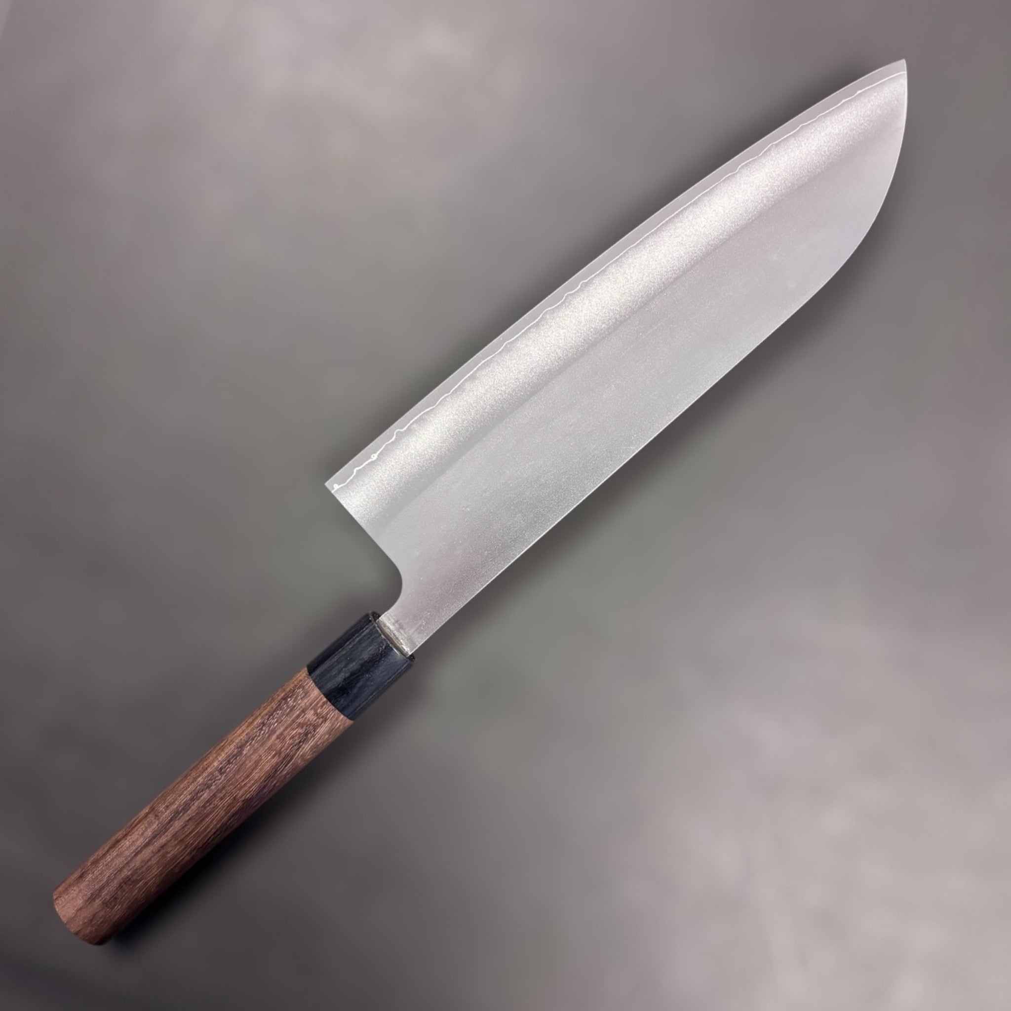 Makoto Kurosaki VG7 Gyuto 240 mm, angled front side showing kasumi finish and subtle cladding line; rosewood wa handle with black ferrule.
