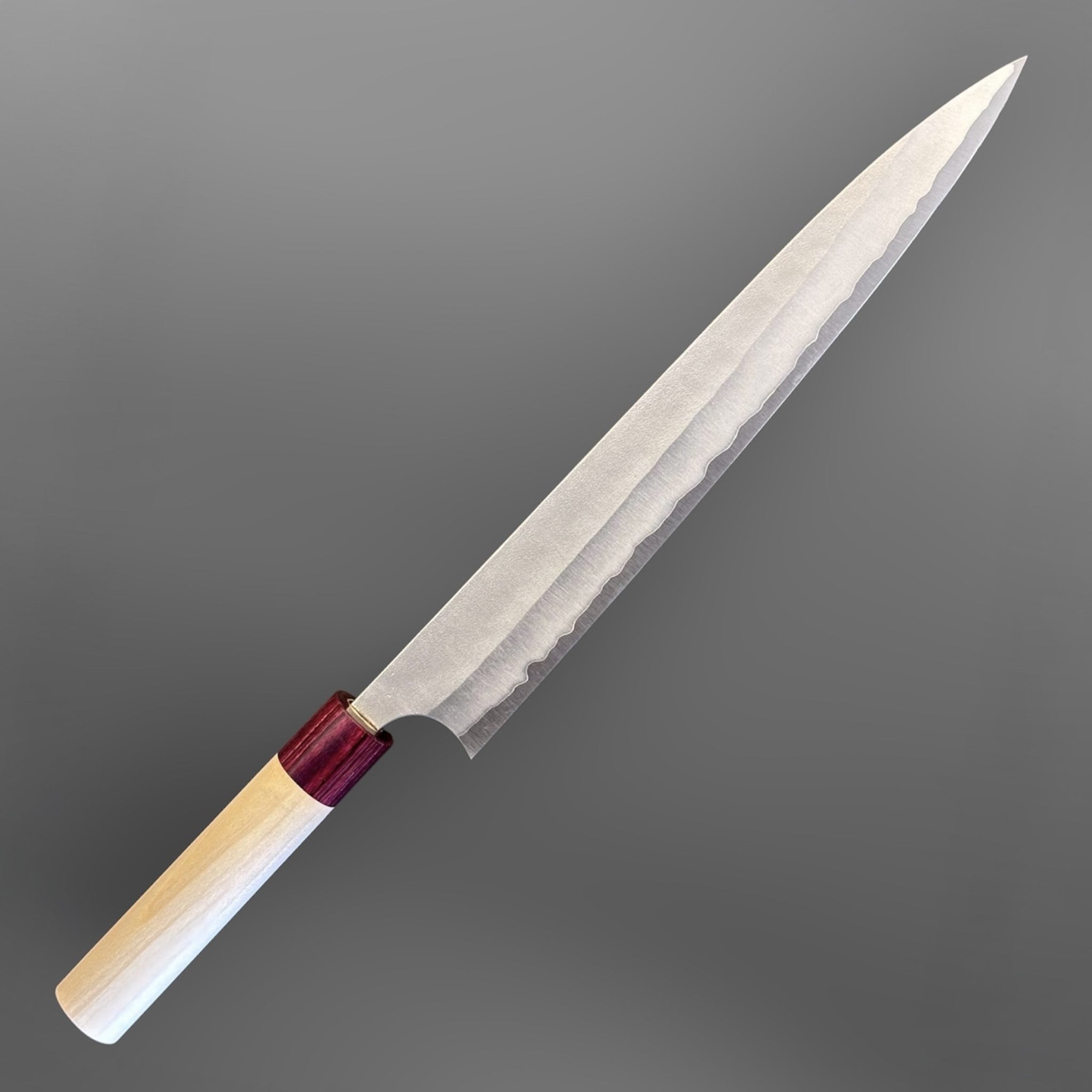 Masakage Yuki Sujihiki 270 mm, angled full view highlighting the slender blade profile and red ferrule handle.