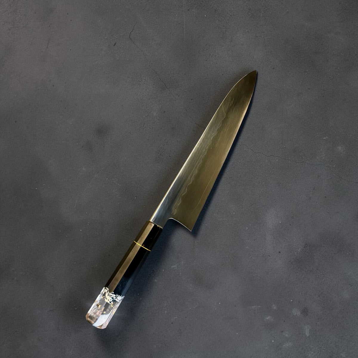 Angled view of the Nakagawa White #2 honyaki gyuto and its black Prisma handle with clear decorative butt