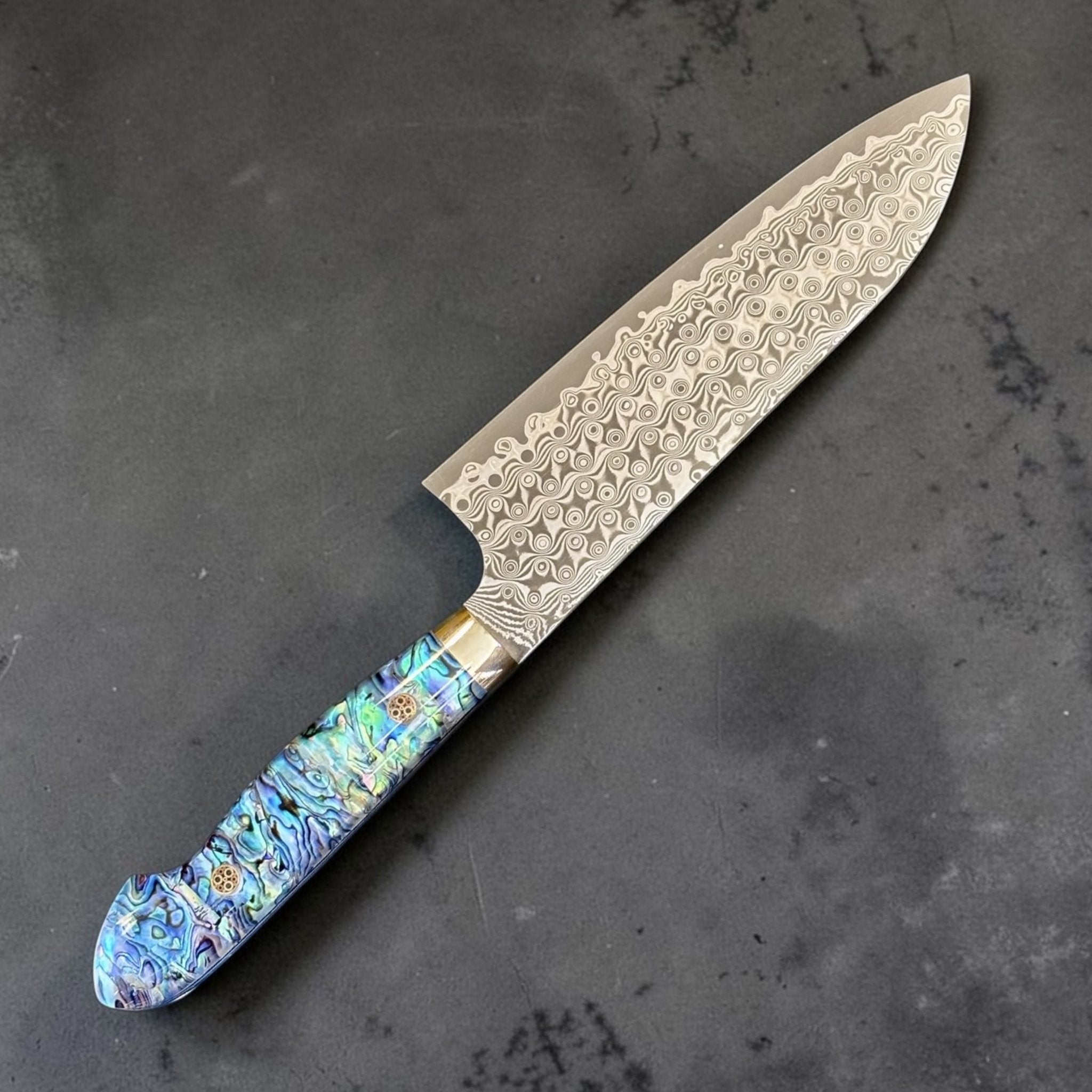 Nigara Anmon Damascus Santoku SG2 180 mm with Abalone Western Handle, angled view highlighting the Anmon Damascus blade pattern and colorful abalone western handle.