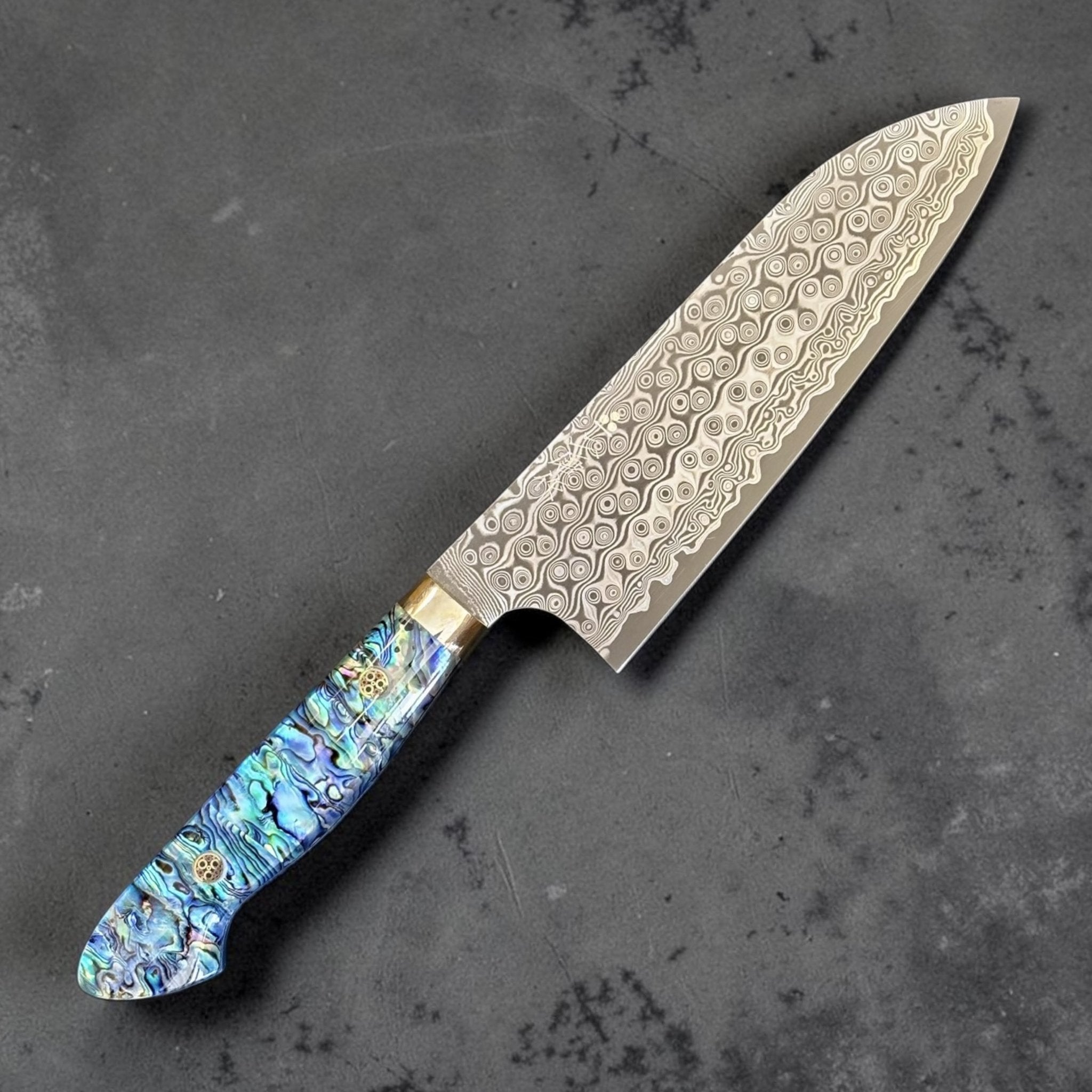 Nigara Anmon Damascus Santoku SG2 180 mm with Abalone Western Handle, close angled view of the santoku blade tip, Anmon Damascus pattern, and abalone western handle.