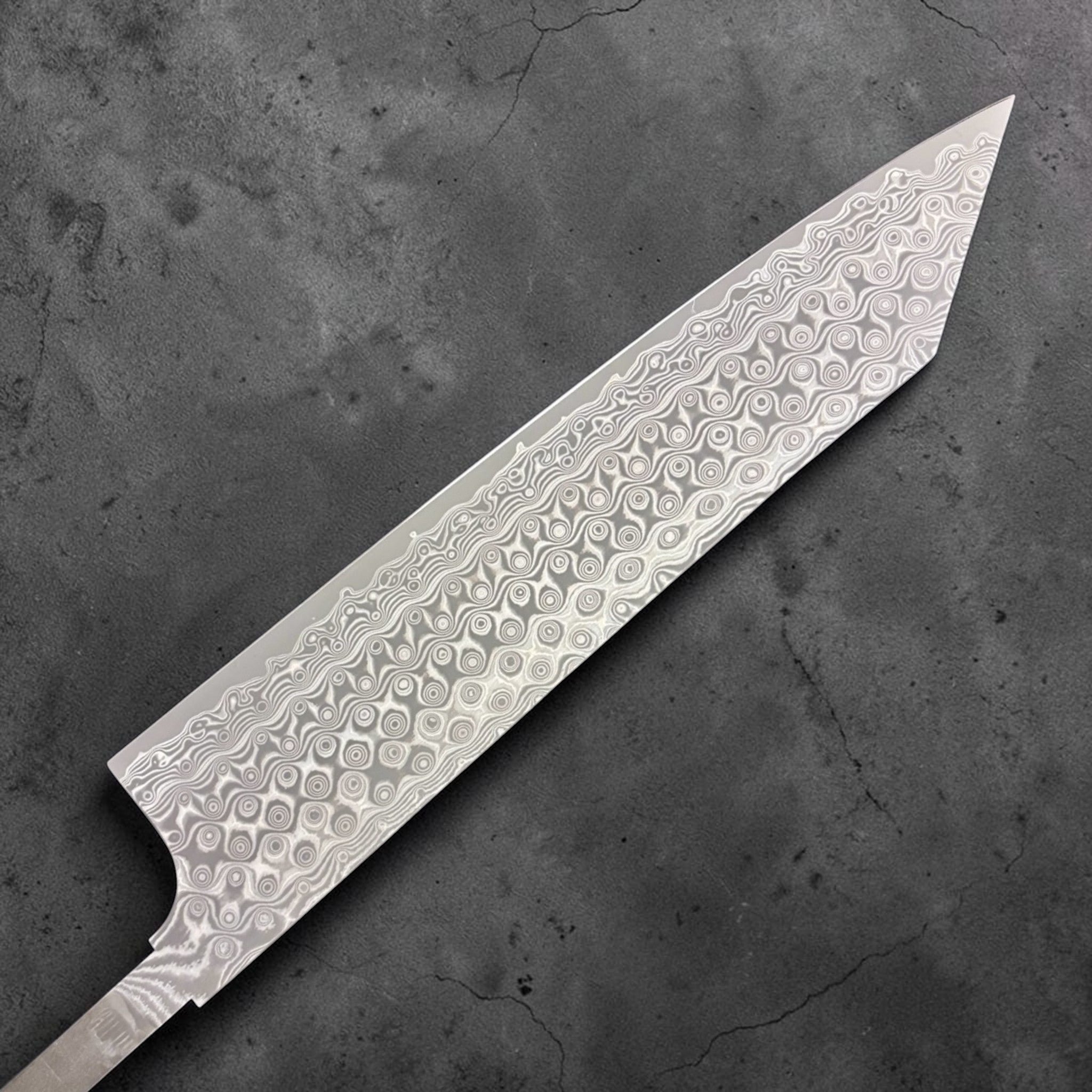 Nigara Anmon SG2 Kiritsuke Gyuto 240 mm, close-up of the Damascus Anmon pattern showing layered steel rings and wavy lines on a kiritsuke-style blade. Left side of blade.