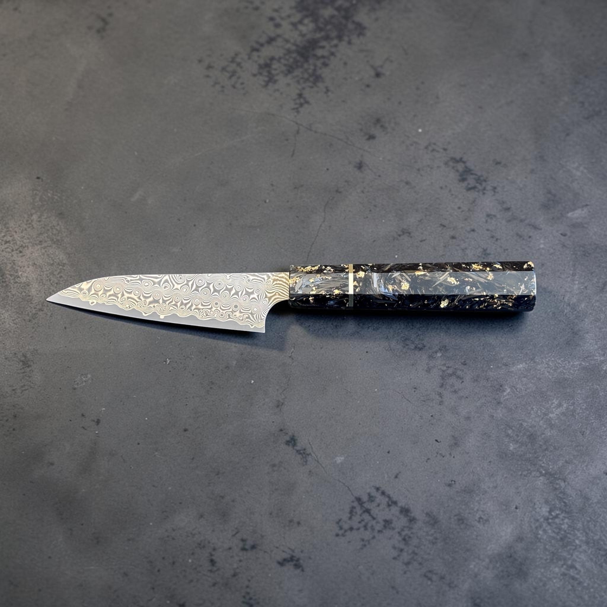 Nigara Anmon SG2 Petty 120 mm with carbon fiber and gold fleck handle, reverse horizontal profile view.
