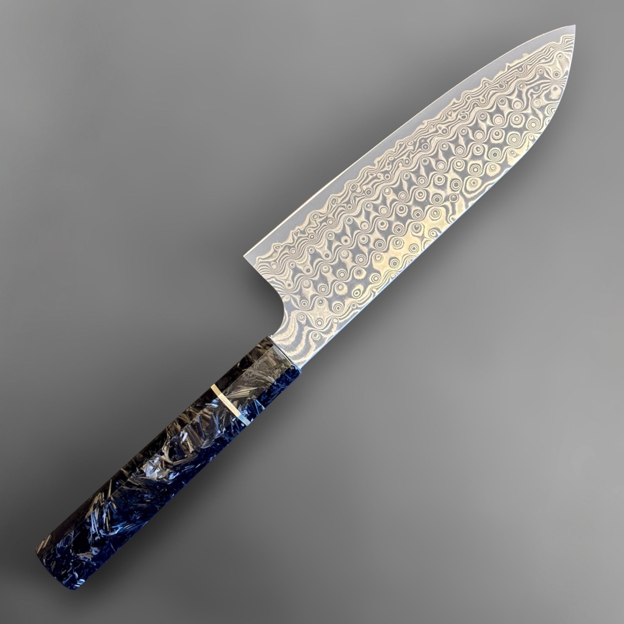Nigara Anmon SG2 Santoku with carbon fiber wa handle, reverse angled product view highlighting layered blade pattern and dark blue handle.