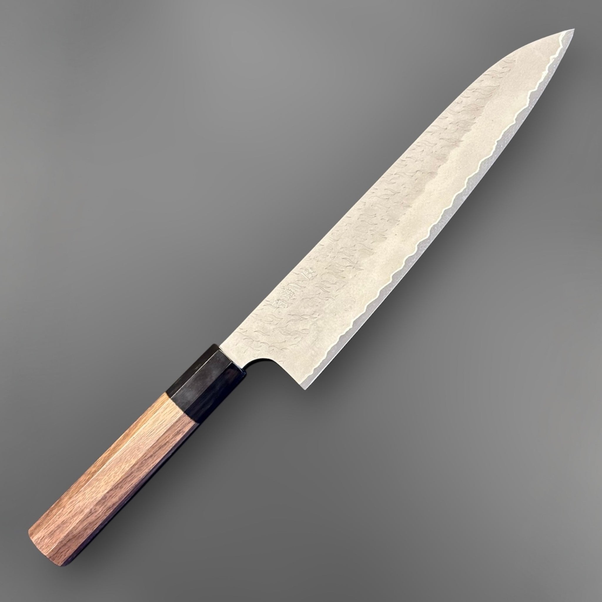 Nigara Aogami Super Steel Tsuchime Gyuto 240 mm with walnut and black horn handle, angled front view of the full knife.