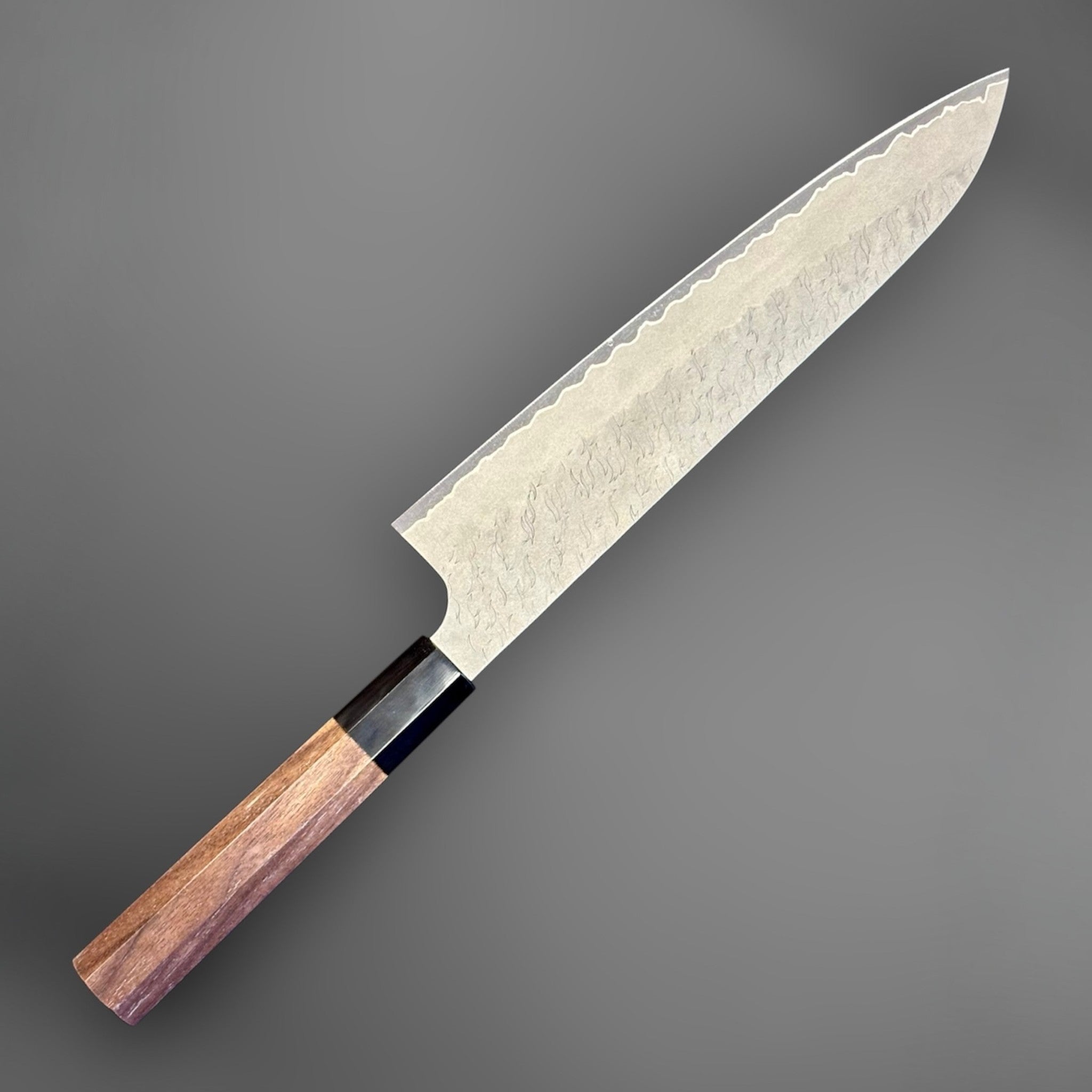 Nigara Aogami Super Steel Tsuchime Gyuto 240 mm with walnut and black horn handle, angled reverse-side view of the blade and handle.