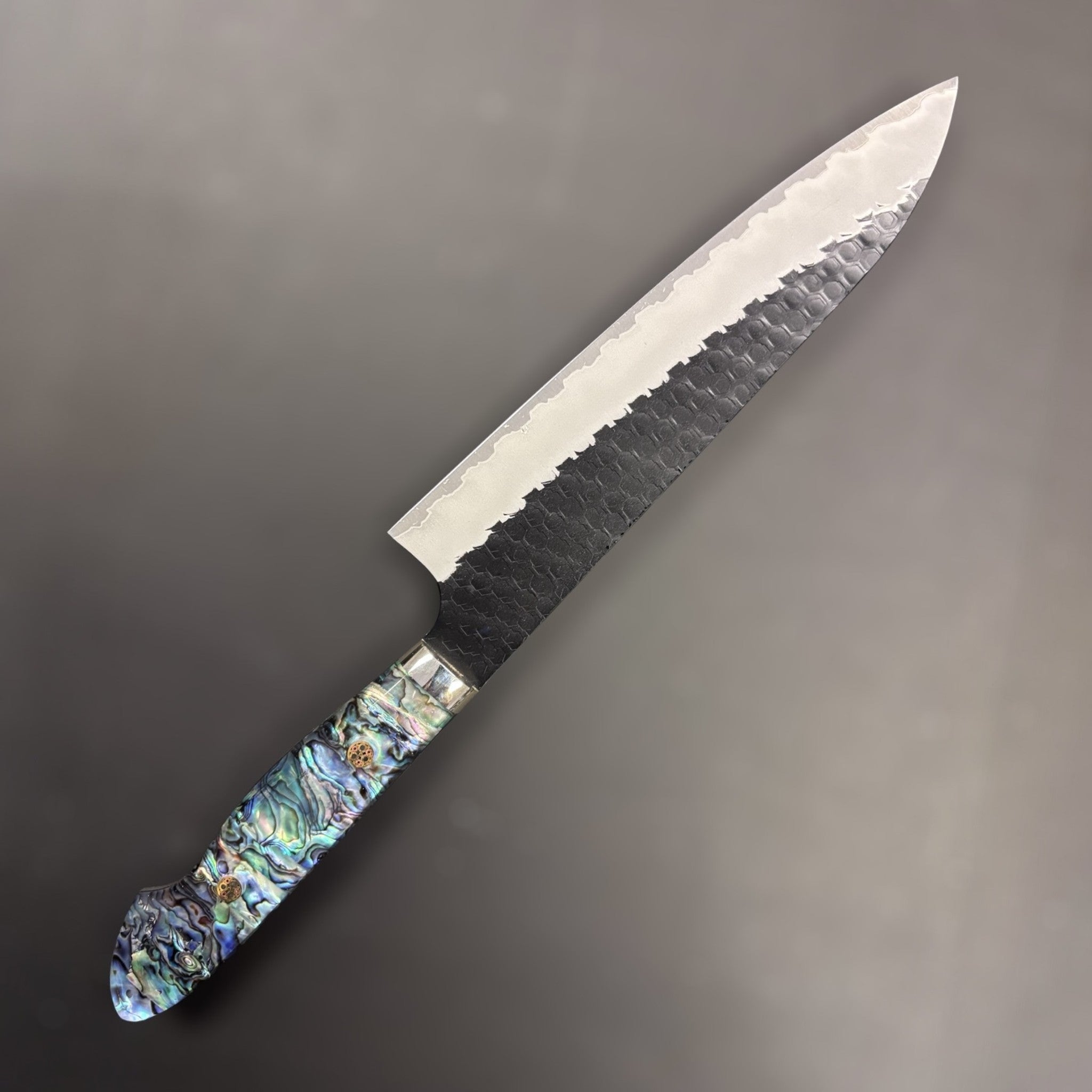 Nigara SG2 Kurouchi Tsuchime Gyuto 210 mm, left side profile highlighting the dark kurouchi cladding and iridescent handle.