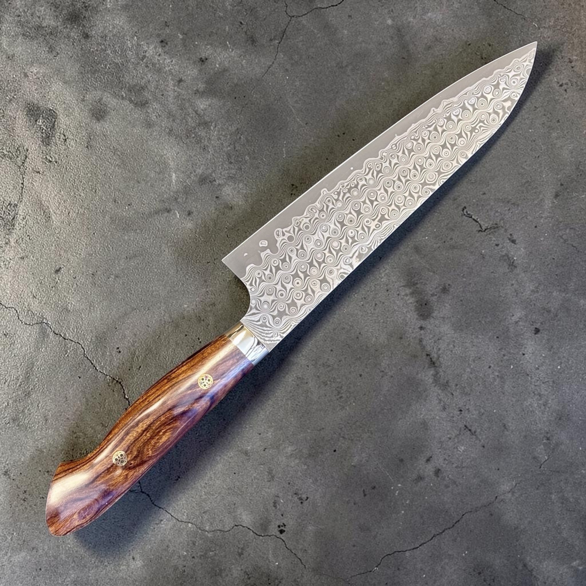 Nigara Hamono Anmon SG2 210 mm Gyuto with ironwood western handle, angled full knife view showing patterned blade and ironwood handle.
