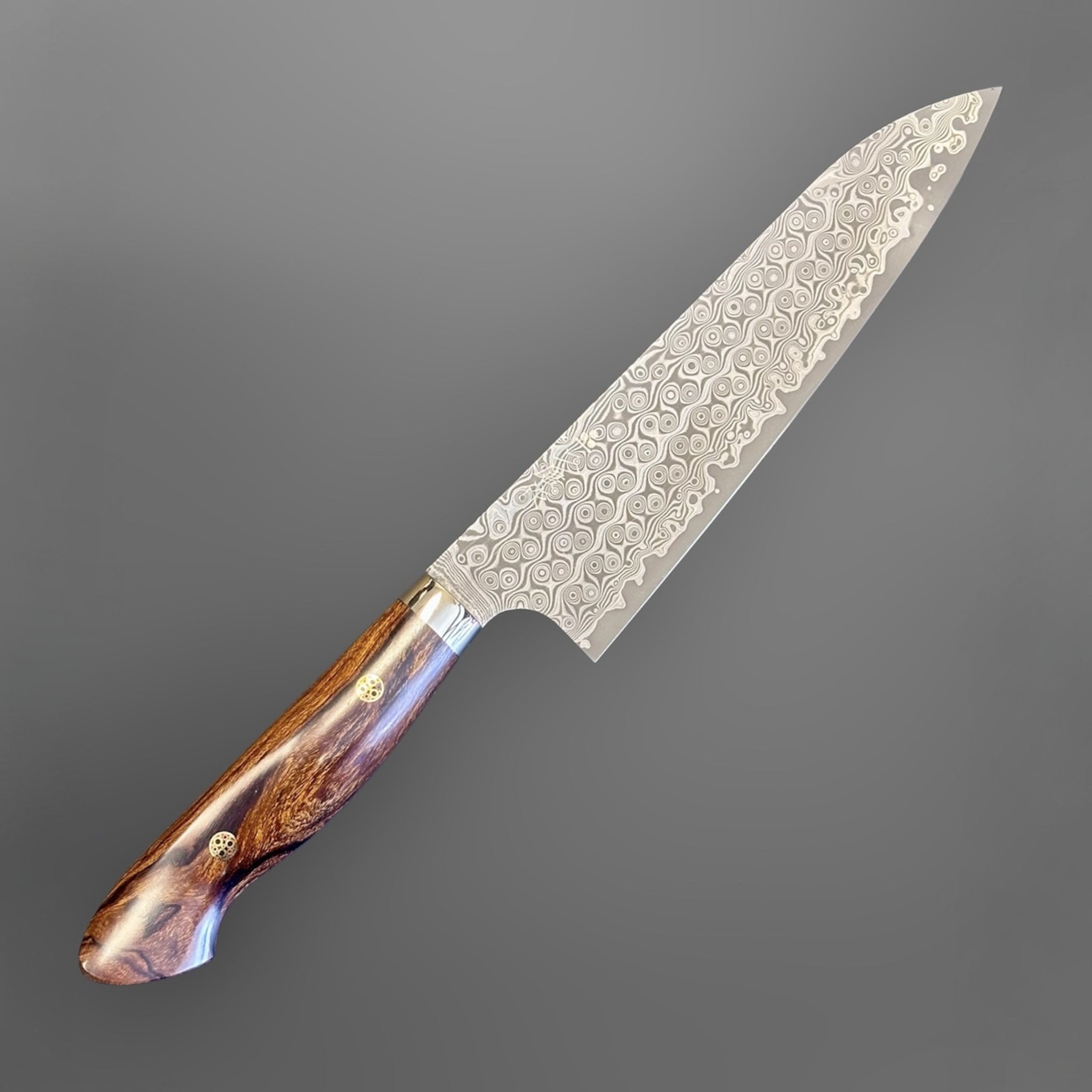 Nigara Hamono Anmon SG2 210 mm Gyuto with ironwood western handle, angled blade view highlighting Anmon Damascus pattern.