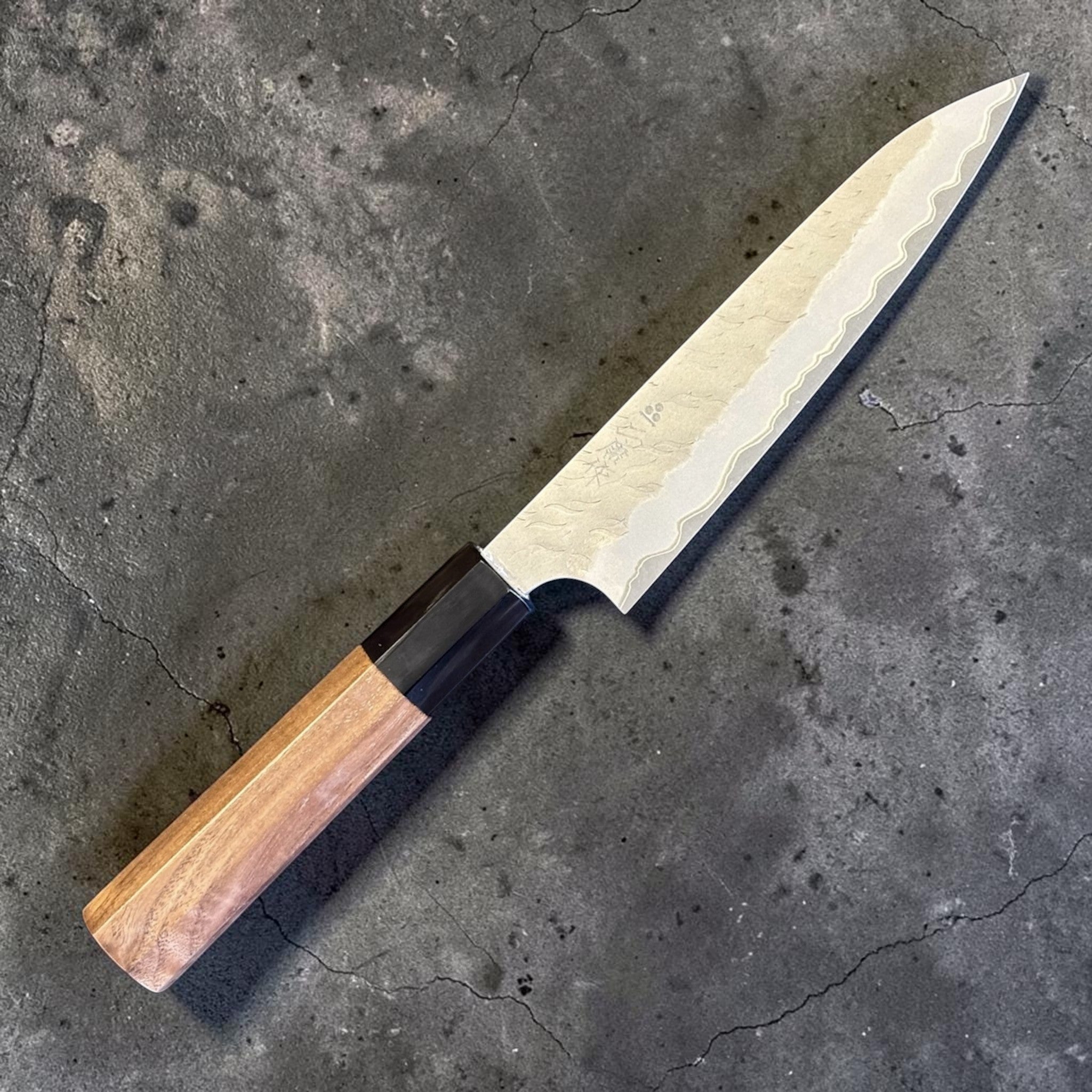 Nigara Hamono Aogami Super Tsuchime Petty 150 mm with walnut horn handle, angled full knife view.
