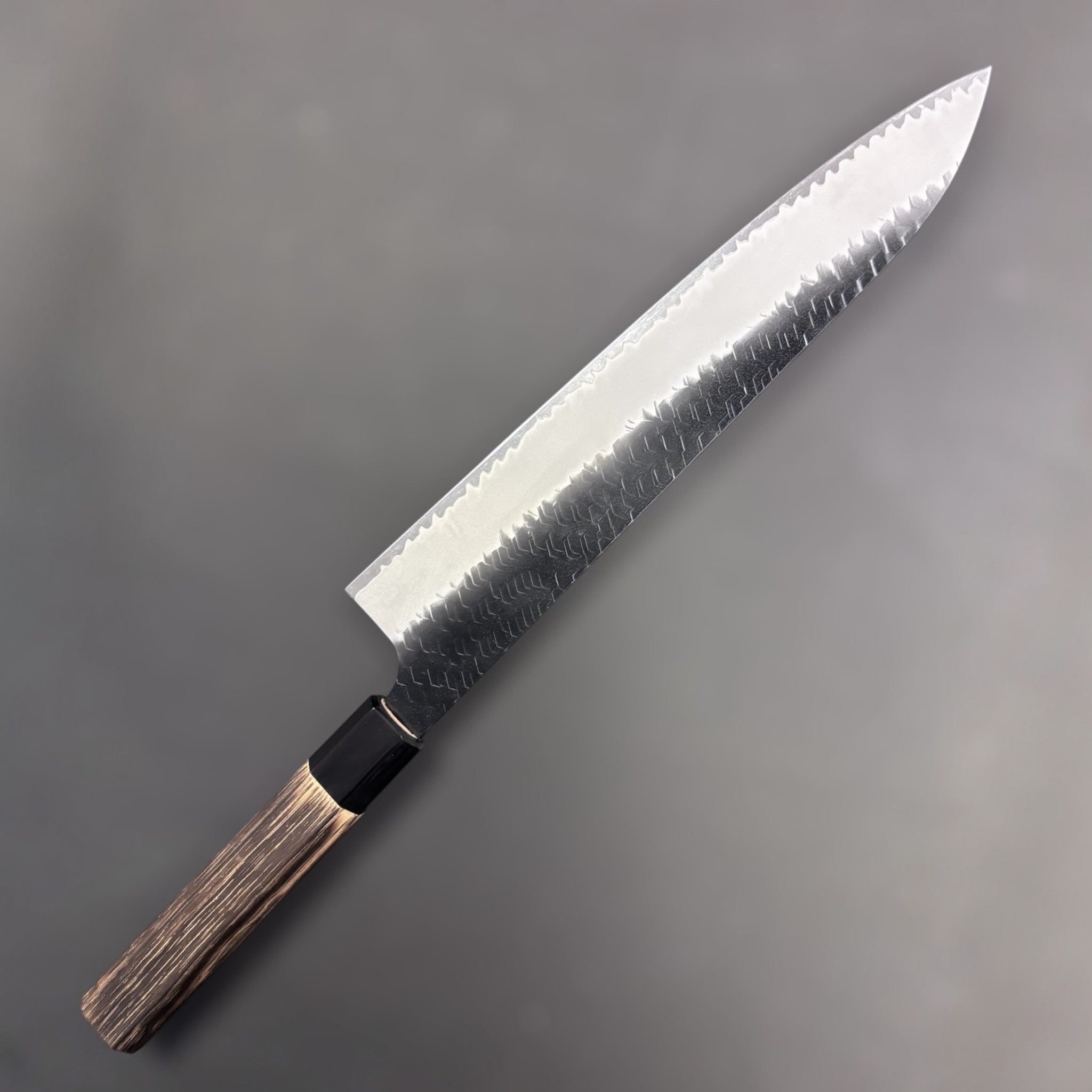 Nigara Hamono SG2 Kurouchi Tsuchime Gyuto 270 mm, front side on neutral background showing hammered cladding and polished core line.