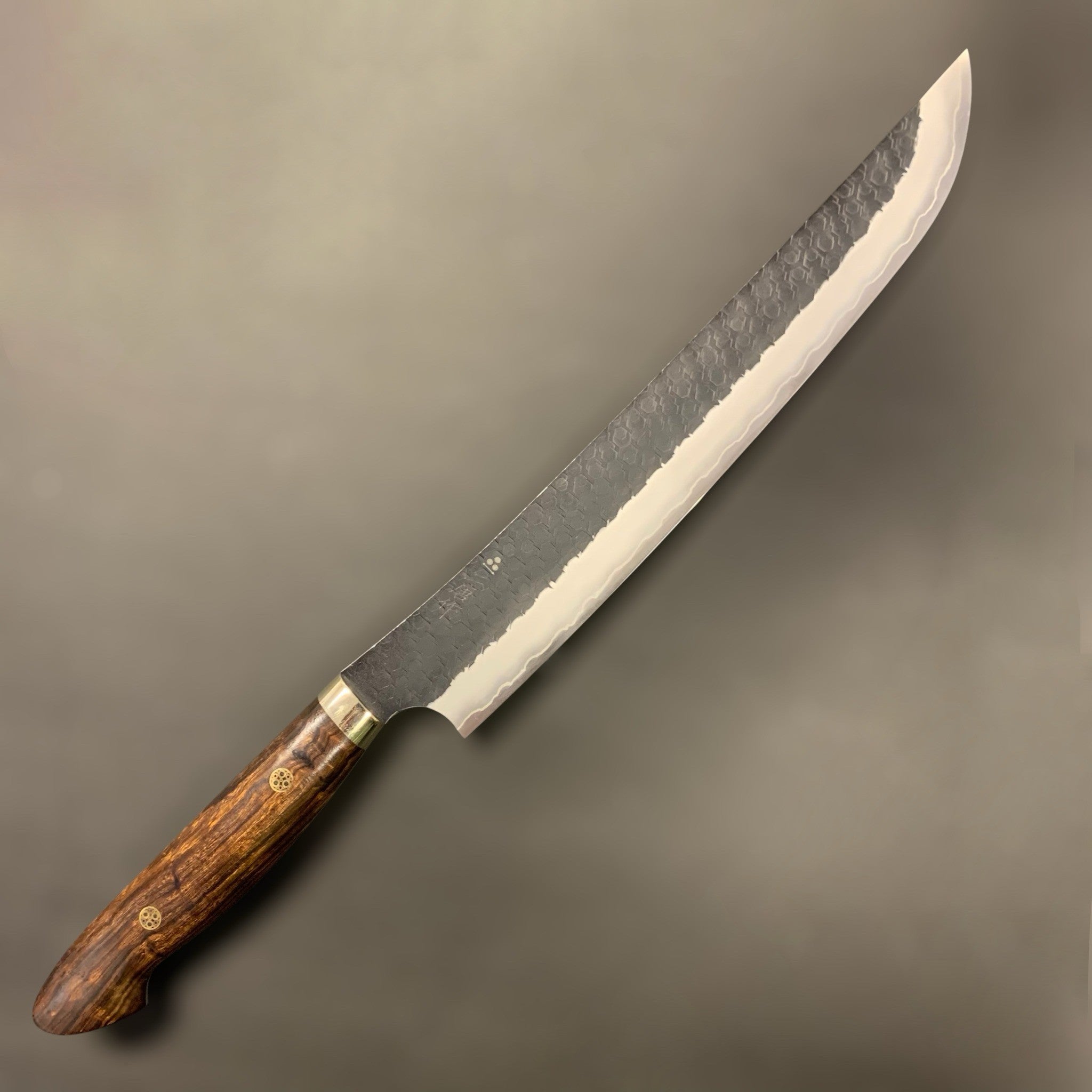 Nigara Hamono SG2 Kurouchi Tsuchime Sakimaru Sujihiki 270 mm, right-side profile showing kurouchi finish and hammered tsuchime pattern with ironwood Western handle.