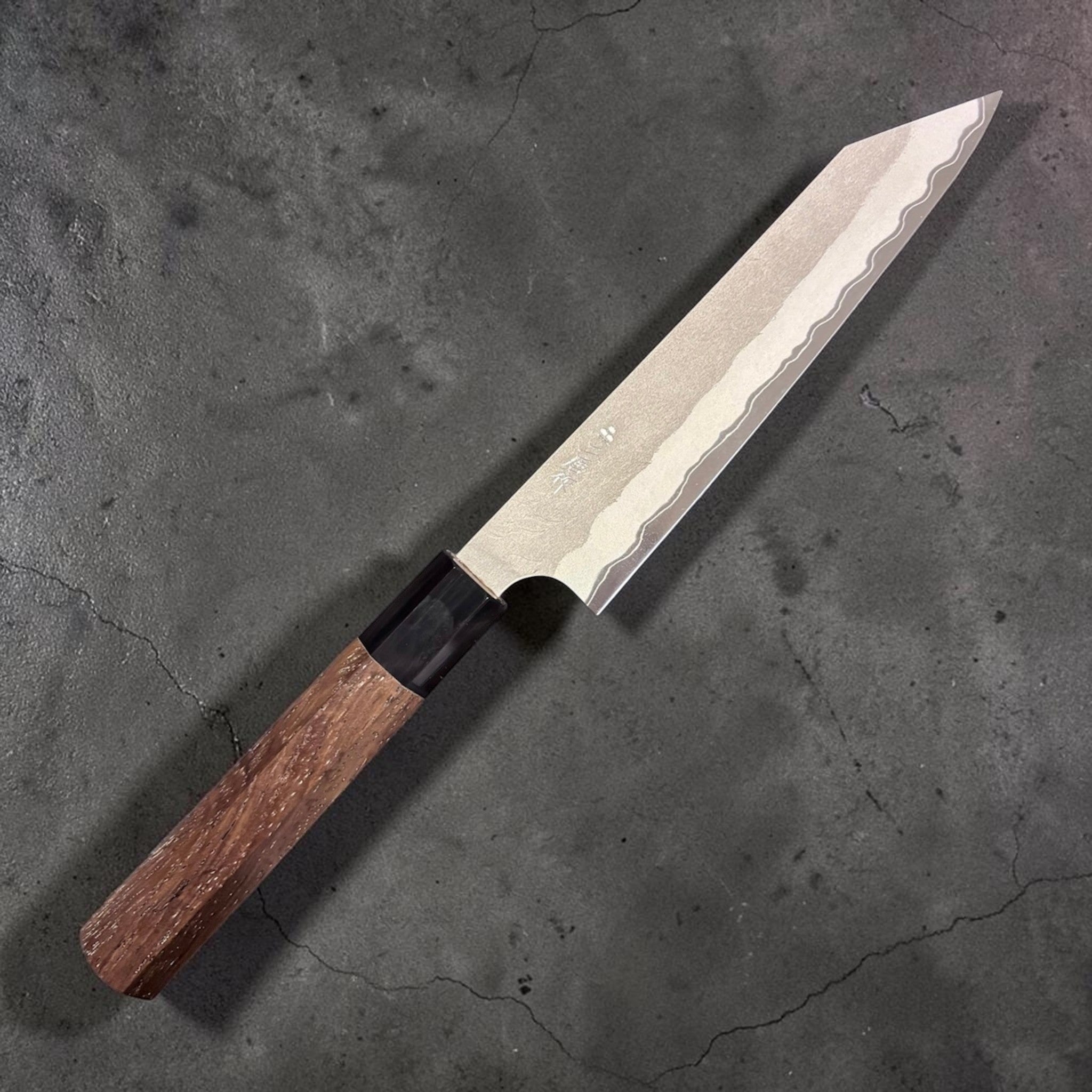 Nigara Hamono Aogami Super Tsuchime Kiritsuke Petty 150 mm with walnut handle, angled view of blade and handle on gray background.