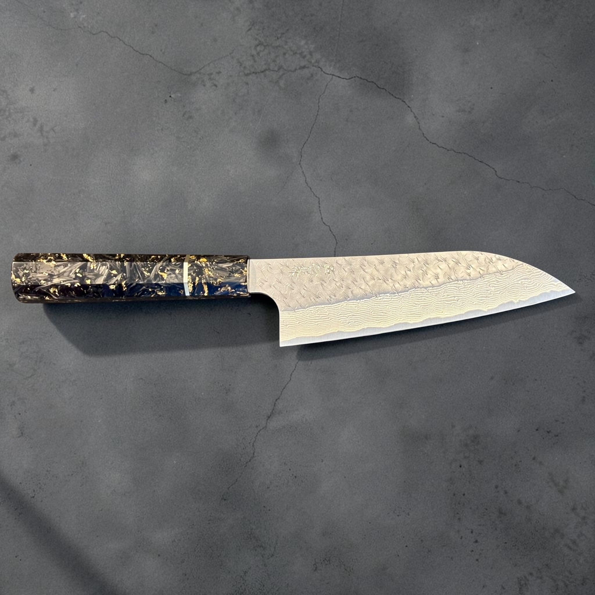 Nigara SG-STRIX Ko Santoku 150 mm chef knife with custom carbon fiber and gold fleck wa handle, full profile showing the hammered Damascus blade and elegant Japanese craftsmanship.