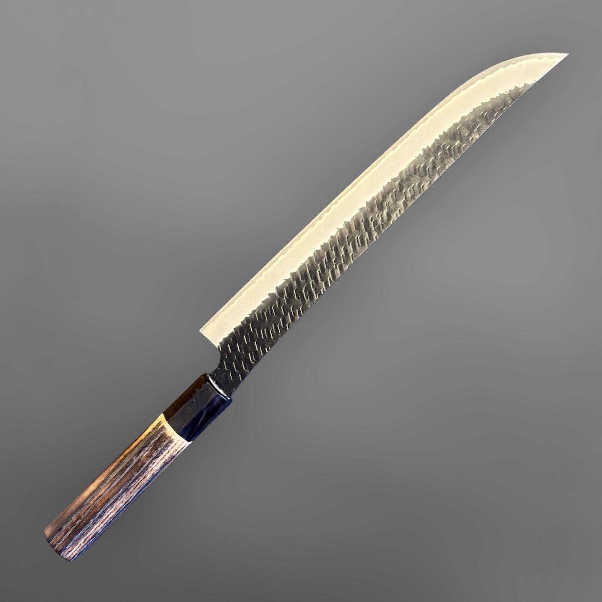 Nigara SG2 Tsuchime Kurouchi Sakimaru Sujihiki 270 mm with wa handle, full angled product view showing the long sakimaru profile and hammered kurouchi blade finish.
