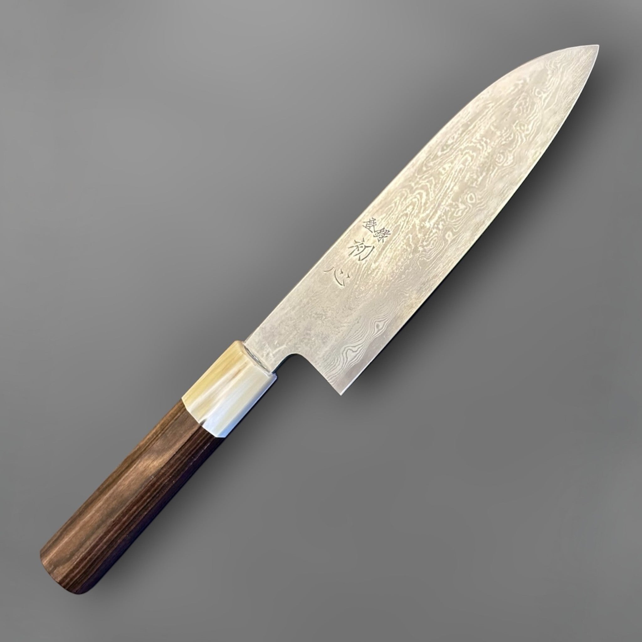 Satoshi Nakagawa Blue #1 Damascus Santoku with ebony and horn handle, angled full product view showing the flowing Damascus pattern and polished blade face.