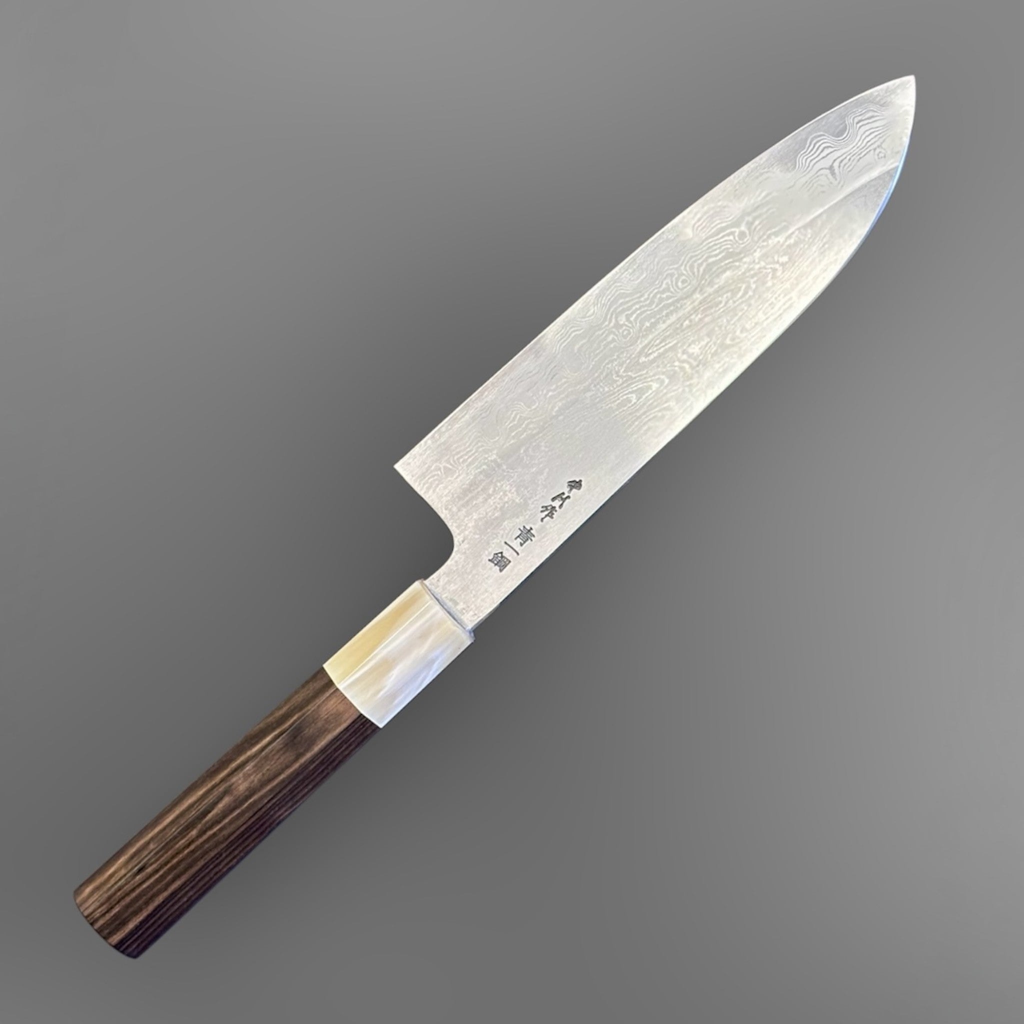 Satoshi Nakagawa Blue #1 Damascus Santoku with ebony and horn handle, reverse angled view highlighting kanji engraving, layered Damascus steel, and dark ebony wa handle with horn ferrule.