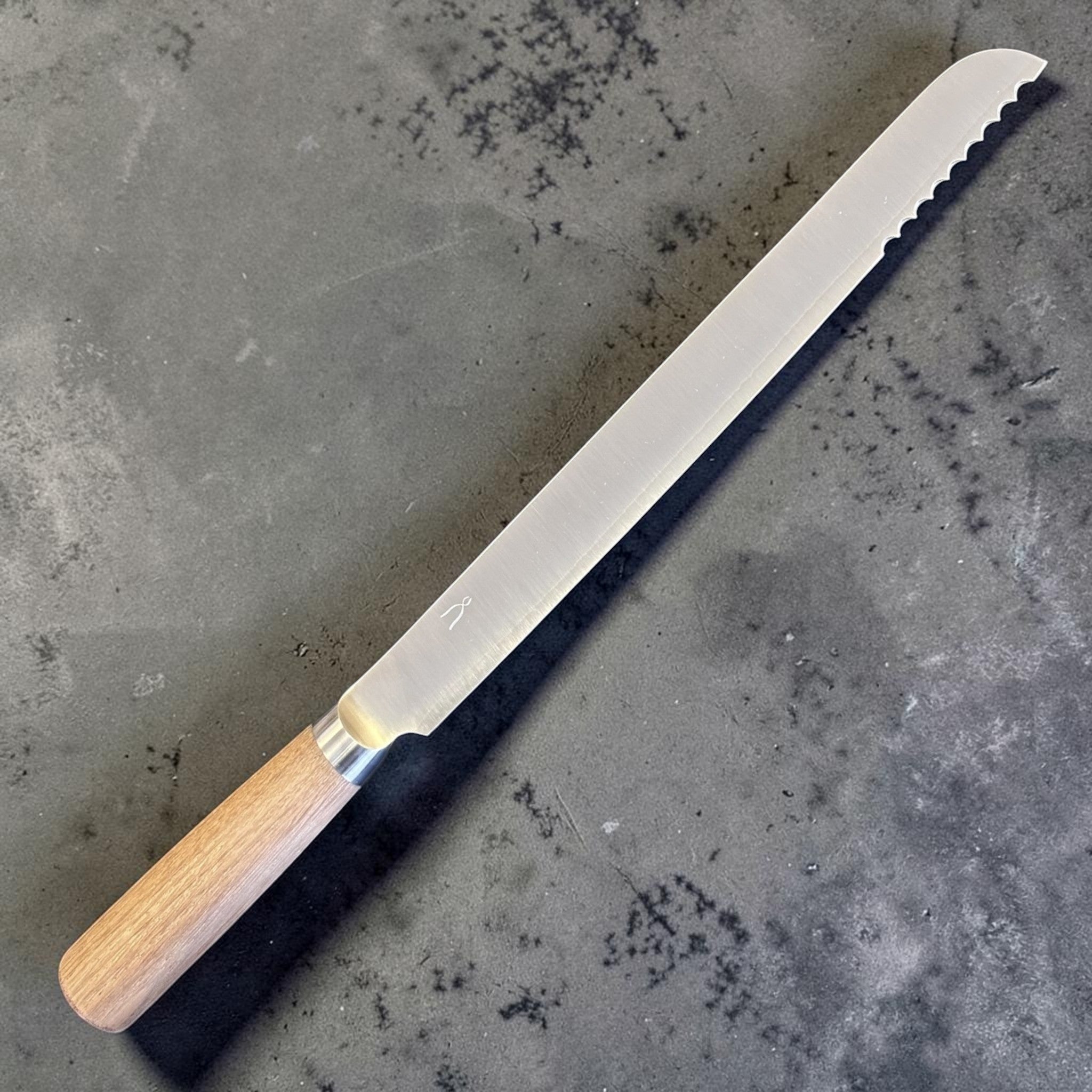 Tadafusa SLD Bread Knife with light wood handle, angled full-profile view showing the serrated tip section.