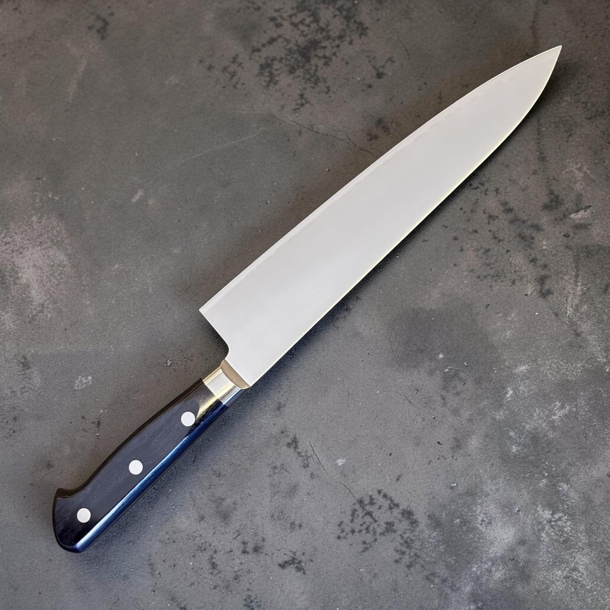 Takamura VG-10 Migaki Gyuto 210 mm with black western handle, clean angled blade profile on gray background.