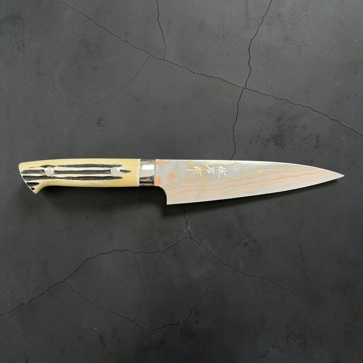 Front profile of Takeshi Saji Blue #2 Rainbow Damascus Petty 130mm with white cow-horn western handle.