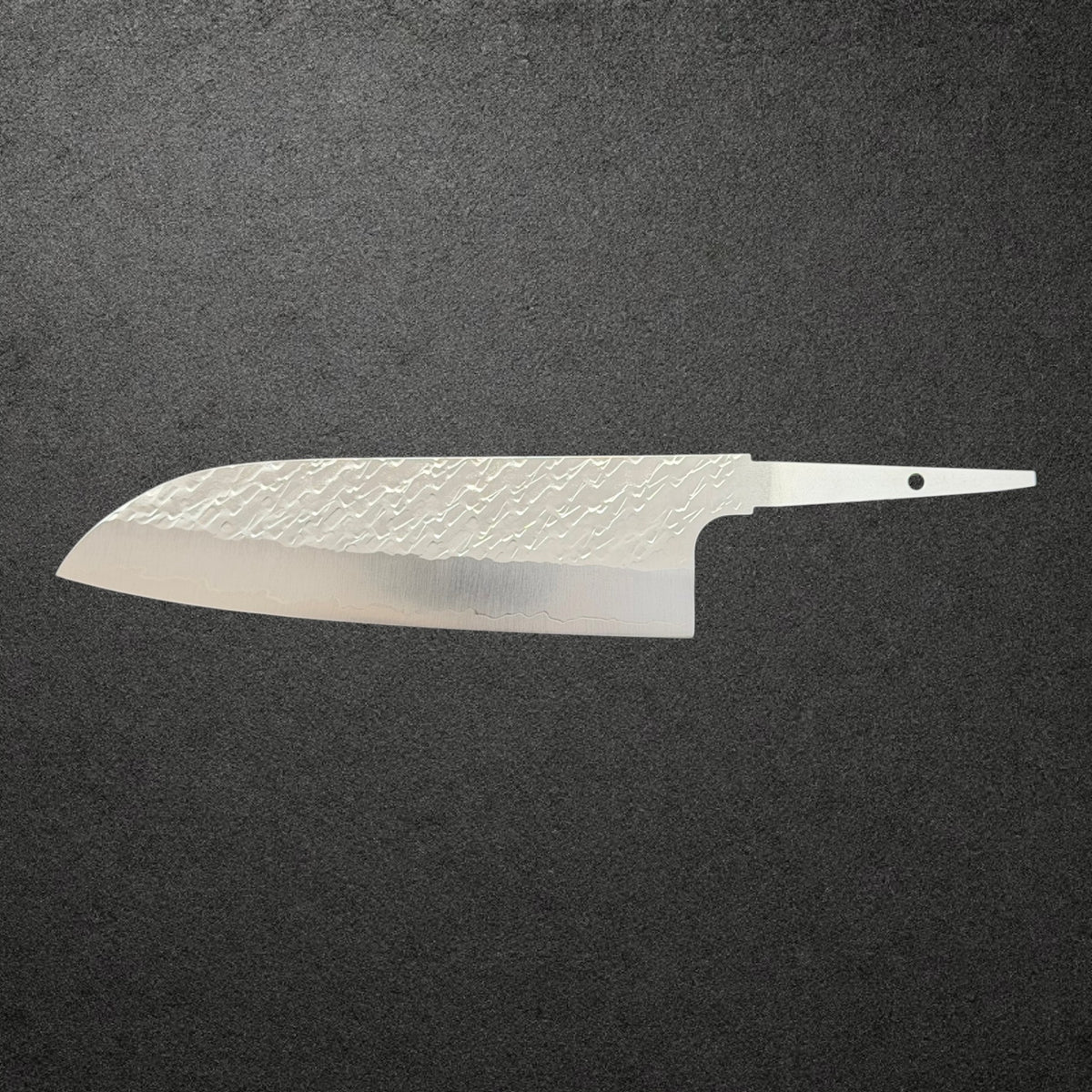 Full reverse profile of Takeshi Saji STRIX Tsuchime Santoku blade only on charcoal concrete.