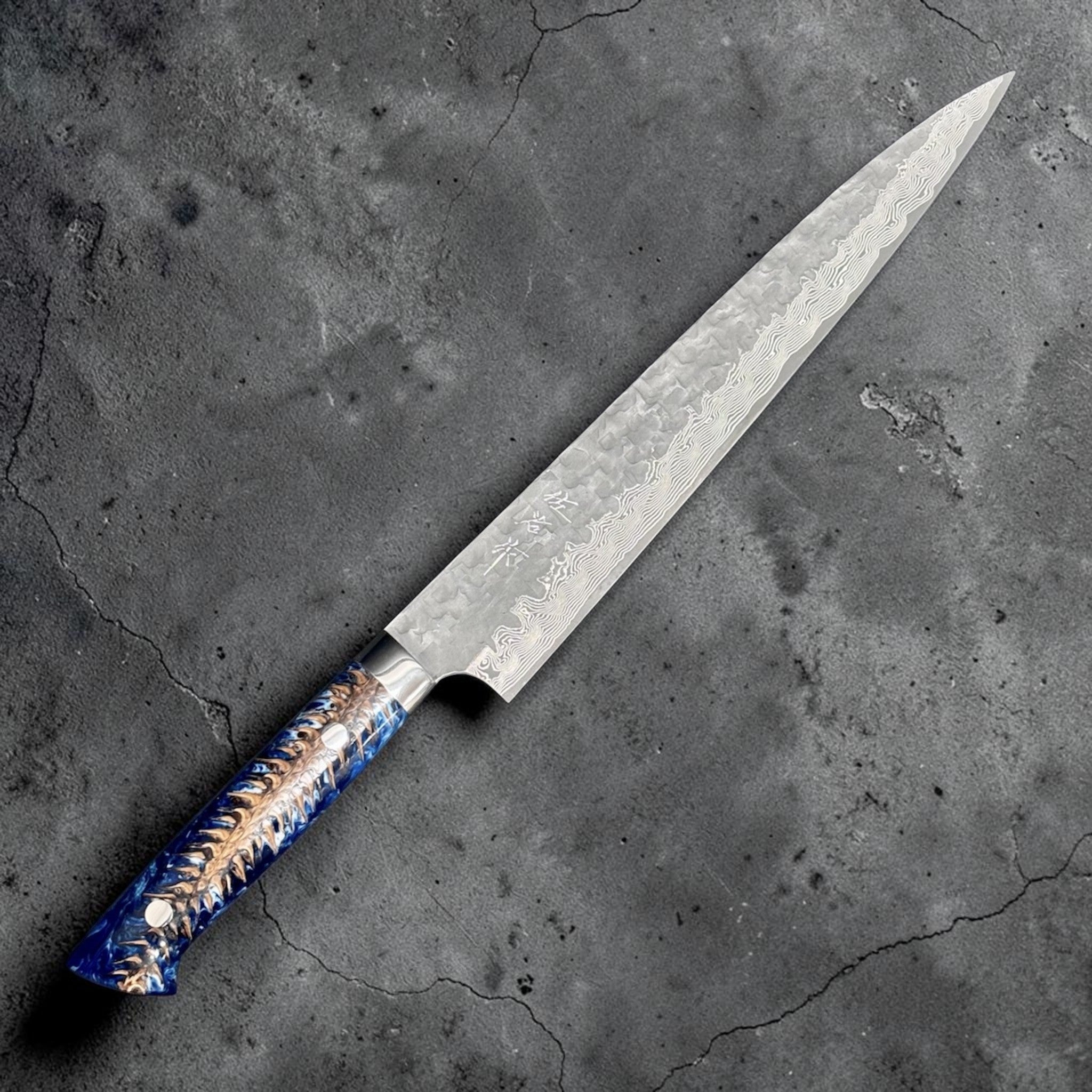Takeshi Saji VG-10 Kuro Cross Tsuchime Sujihiki 240 mm with pinecone resin western handle, angled full-profile view showing the Damascus edge band and hammered blade texture.