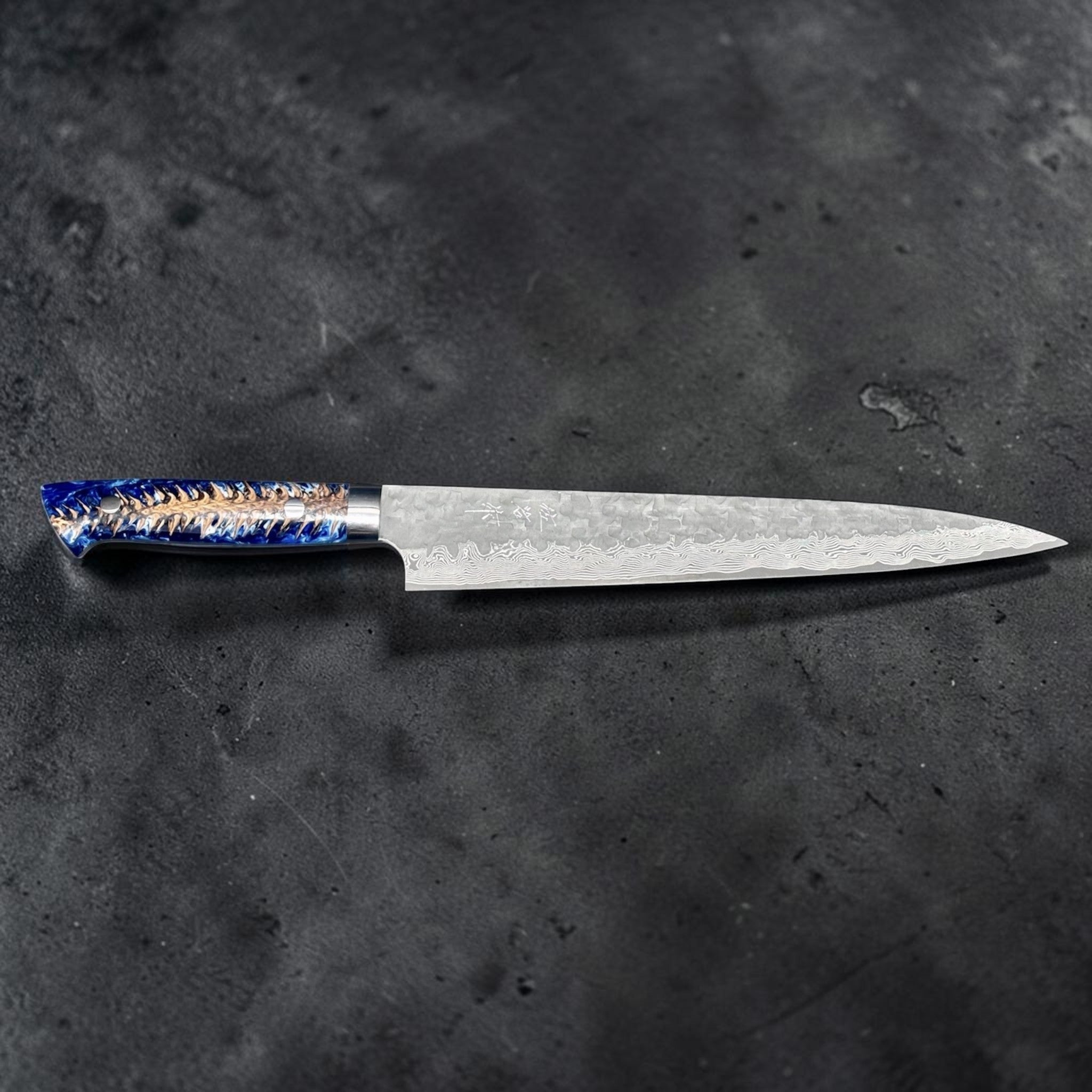 Takeshi Saji VG-10 Kuro Cross Tsuchime Sujihiki 240 mm with pinecone resin western handle, horizontal side profile showing the long slicing blade and blue pinecone resin handle.