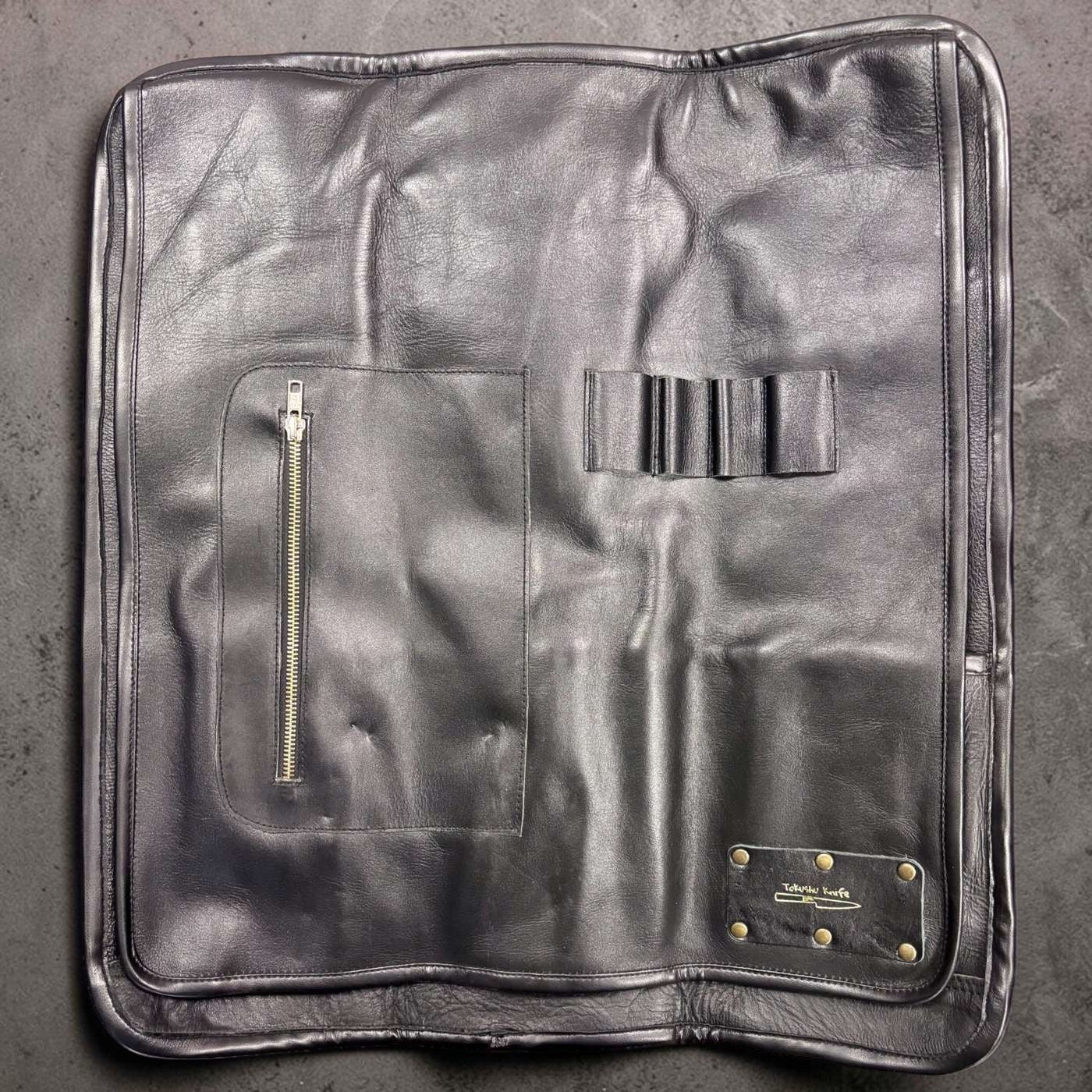 Tokushu Knife Premium Leather Knife Roll interior with zip pocket, elastic tool loops, and brass-riveted Tokushu logo patch