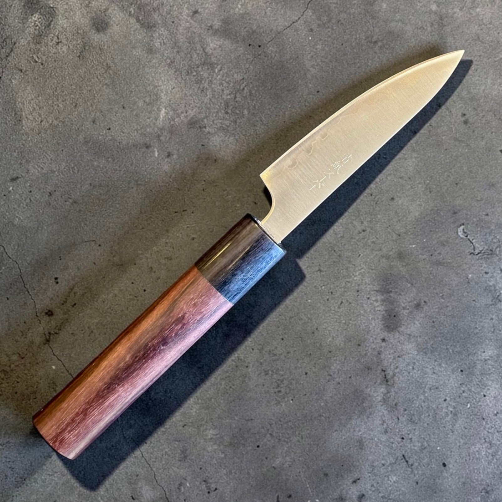 Tokushu Knife Stainless Clad Aogami Super Migaki Petty 80mm, angled reverse-side view showing hamon-like cladding line.