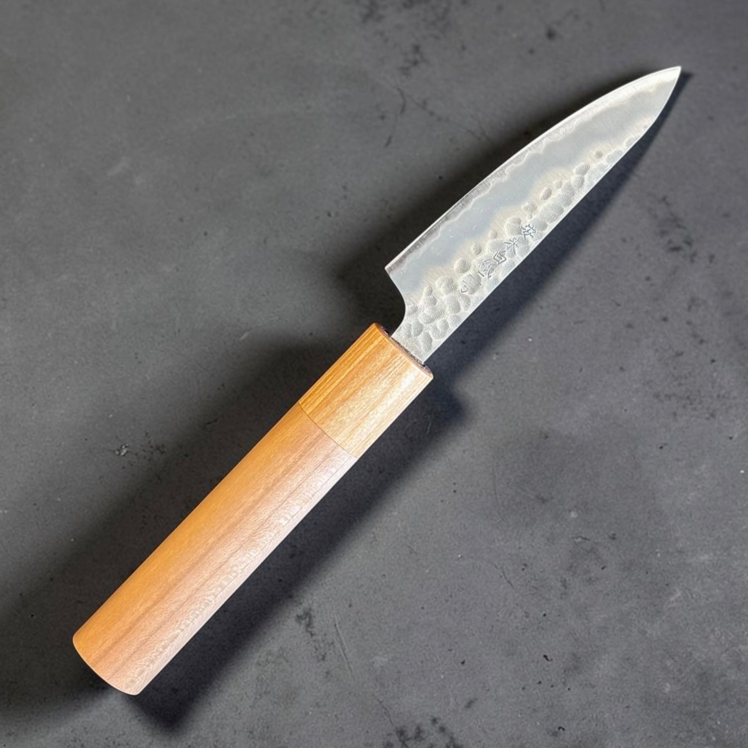 Angled full view of Tokushu Knife Stainless Clad White #2 Tsuchime Petty 80mm with light wood wa handle.