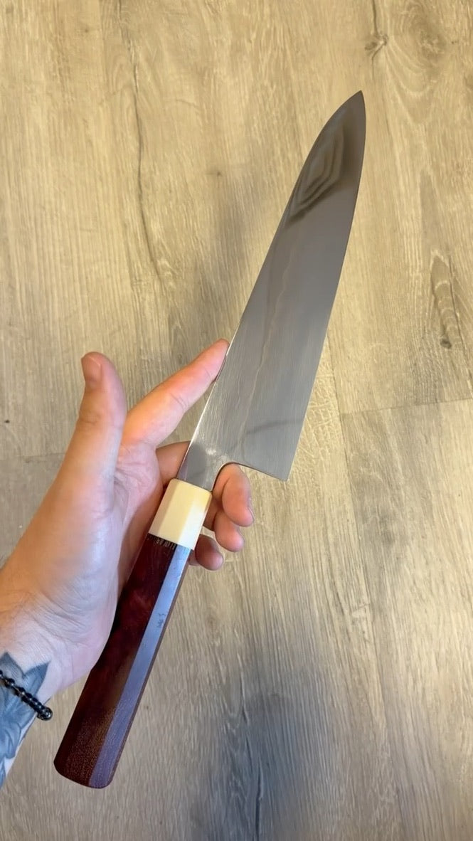 Tokushu Knife Nakagawa and Shuji Yamaguchi White #1 Mizu Honyaki 240mm gyuto with one-of-one red custom handle shown in hand.